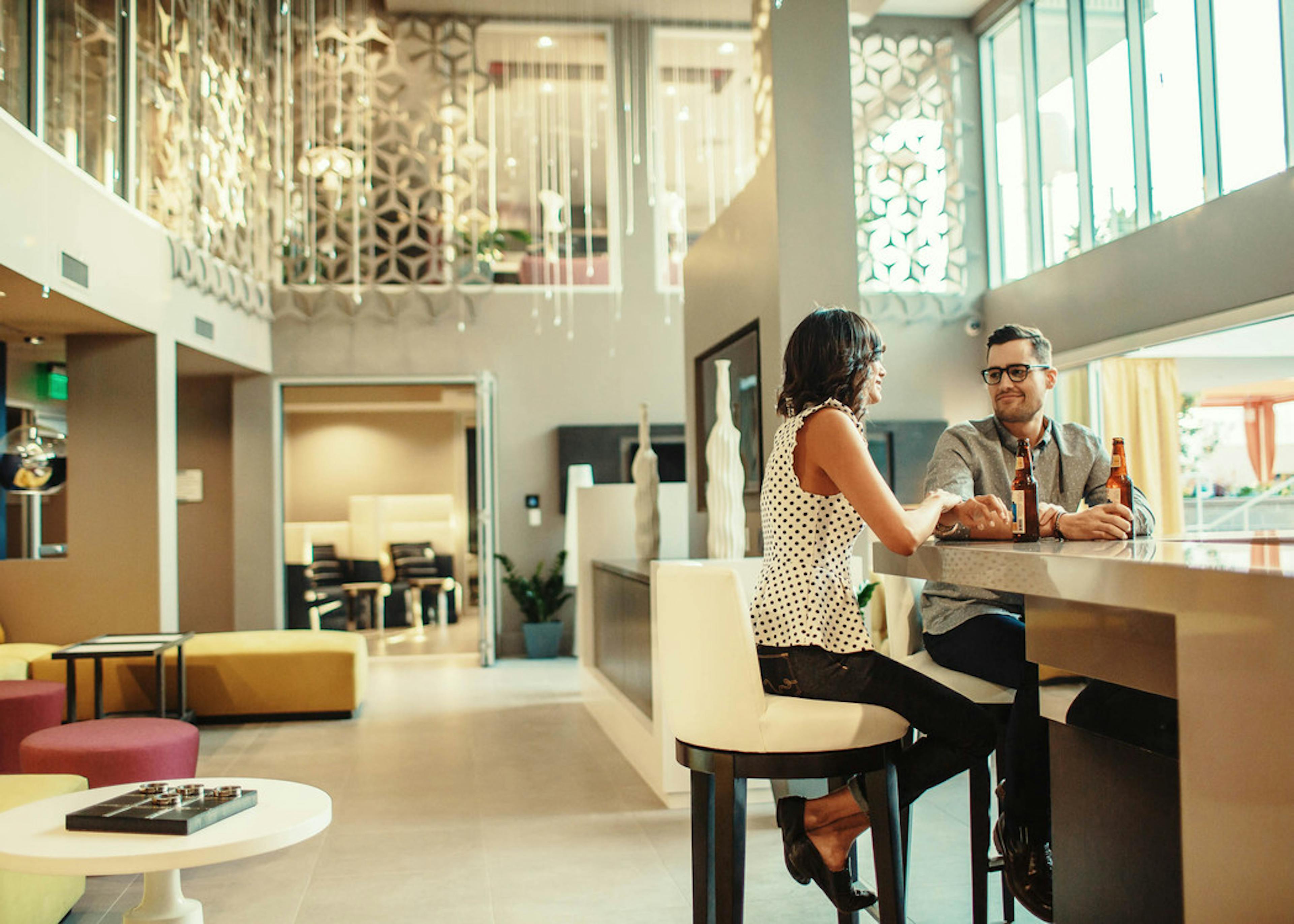 Interior of clubhouse at AMLI Lex on Orange apartments with tall ceilings and a happy couple sitting at the bar and chatting