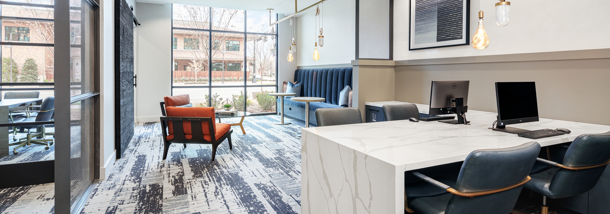 AMLI Addison co working space with white desk and two desktop computers and four grey chairs with seating near large window