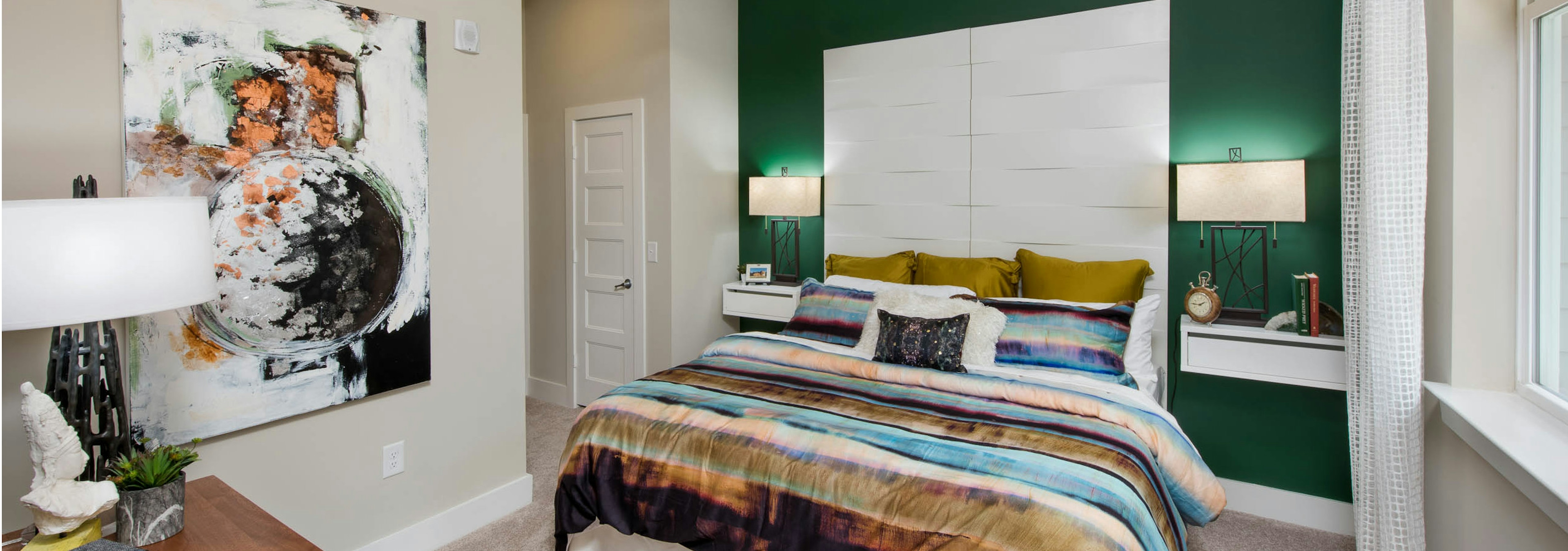 AMLI Buckhead bedroom with emerald accent wall and teal, coral and olive striped bedding with window to the right of the bed