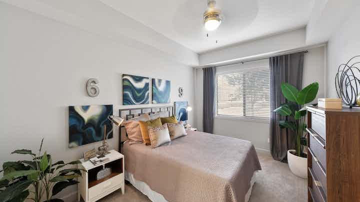 Interior view of an AMLI 8800 apartment bedroom with a bed underneath blue geometric wall art and a window view
