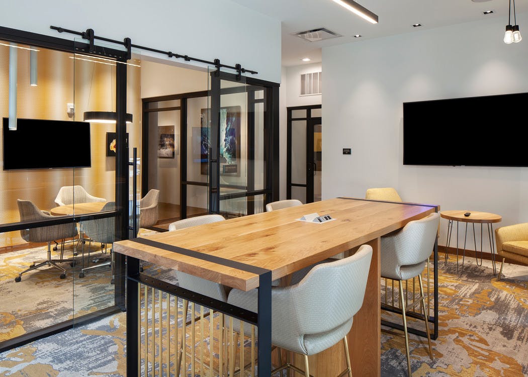 Business center at AMLI Riverfront Green apartments with multiple tables and chairs and a separate conference room area