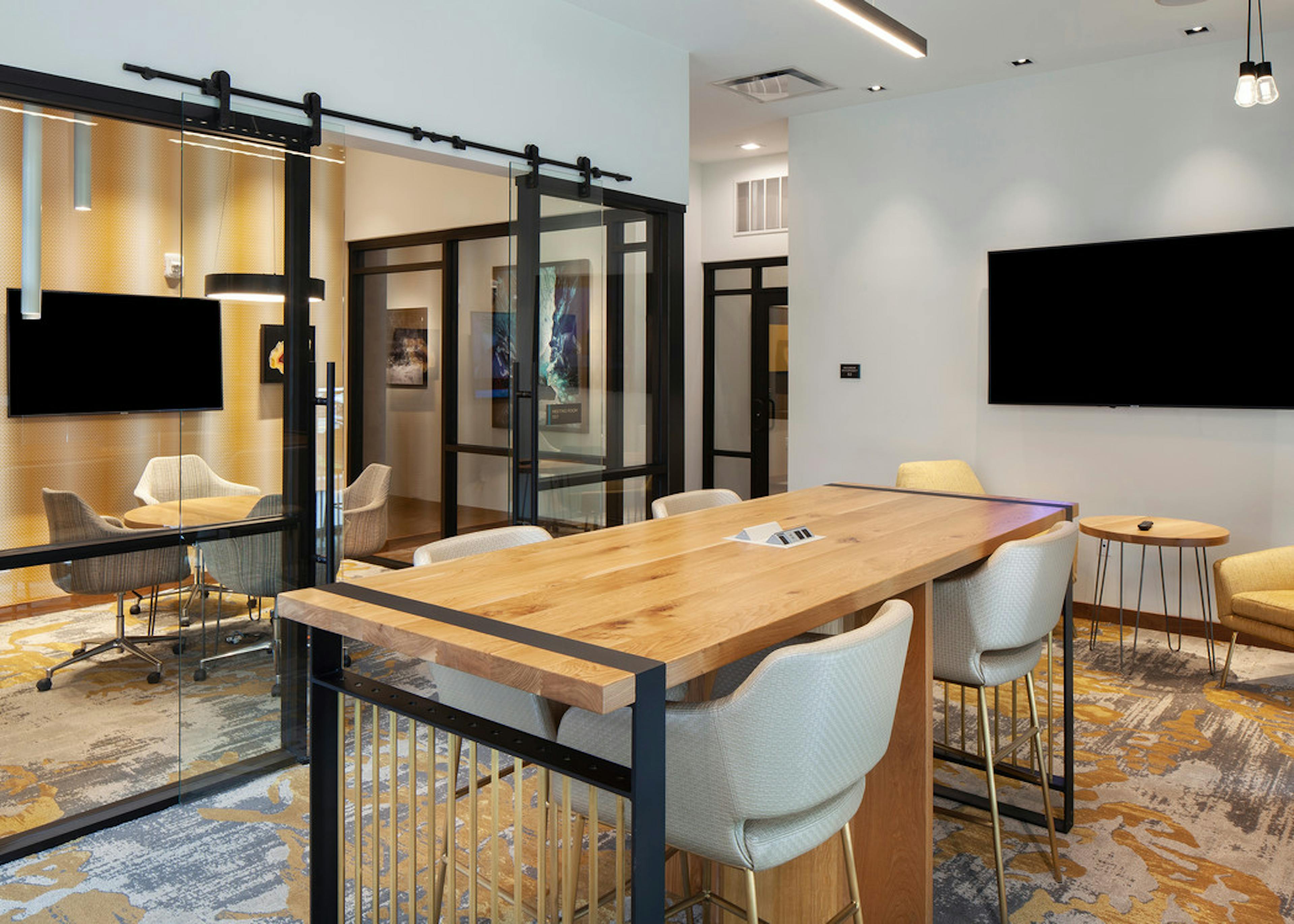 Business center at AMLI Riverfront Green apartments with multiple tables and chairs and a separate conference room area