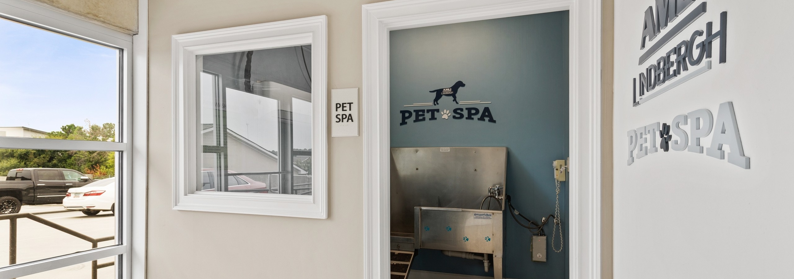 Doorway of pet spa at AMLI Lindbergh apartments showcasing a stainless steel washing station and decorative wall signs