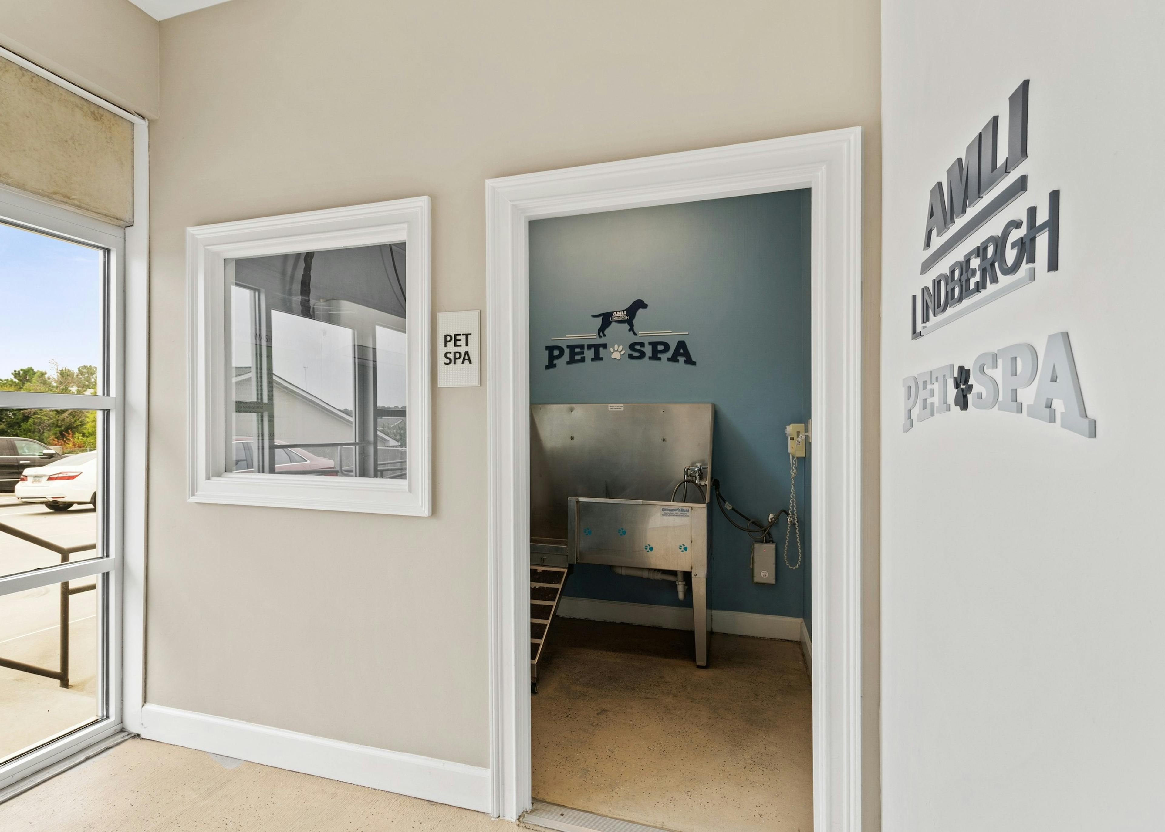 Doorway of pet spa at AMLI Lindbergh apartments showcasing a stainless steel washing station and decorative wall signs