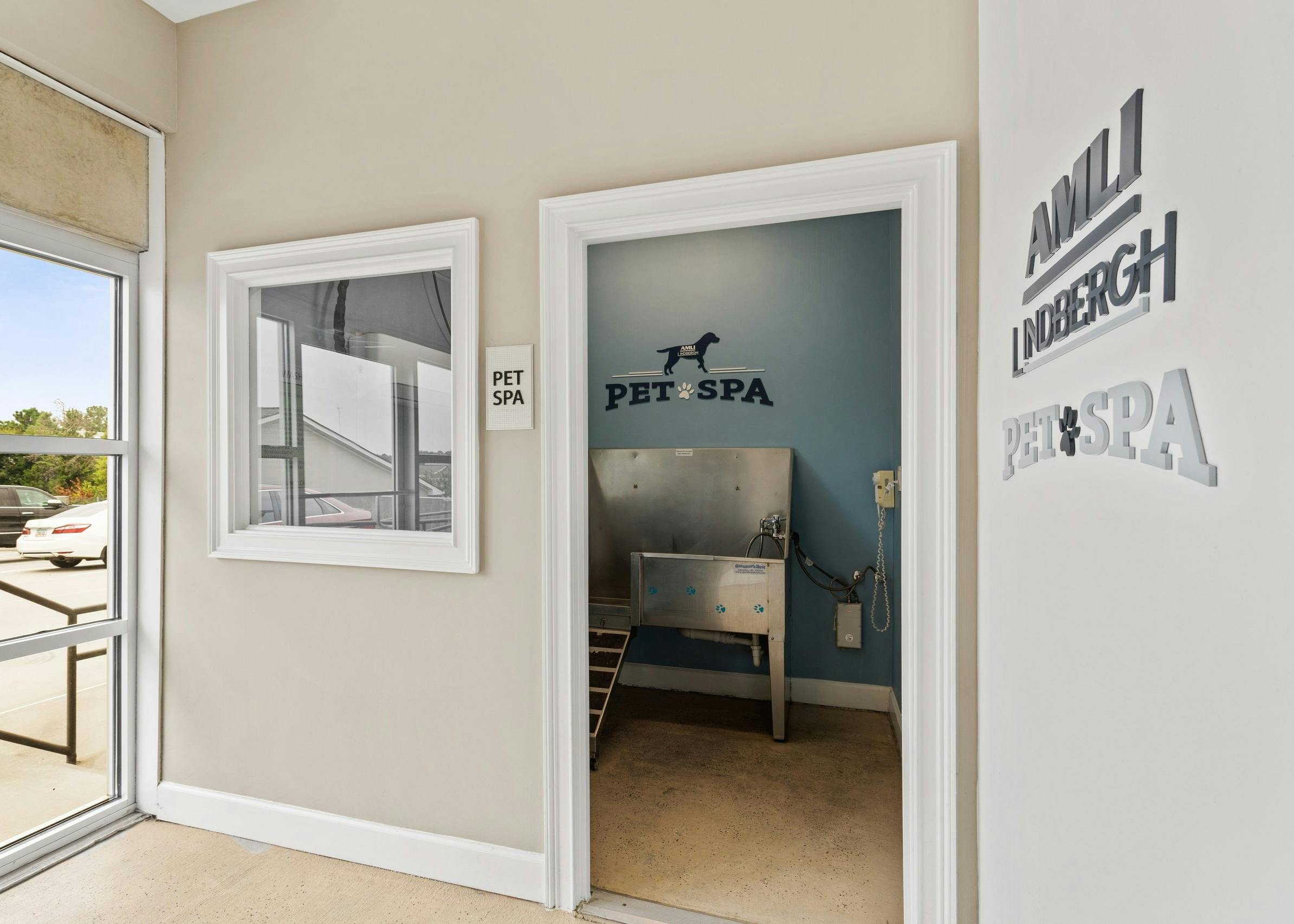 Doorway of pet spa at AMLI Lindbergh apartments showcasing a stainless steel washing station and decorative wall signs