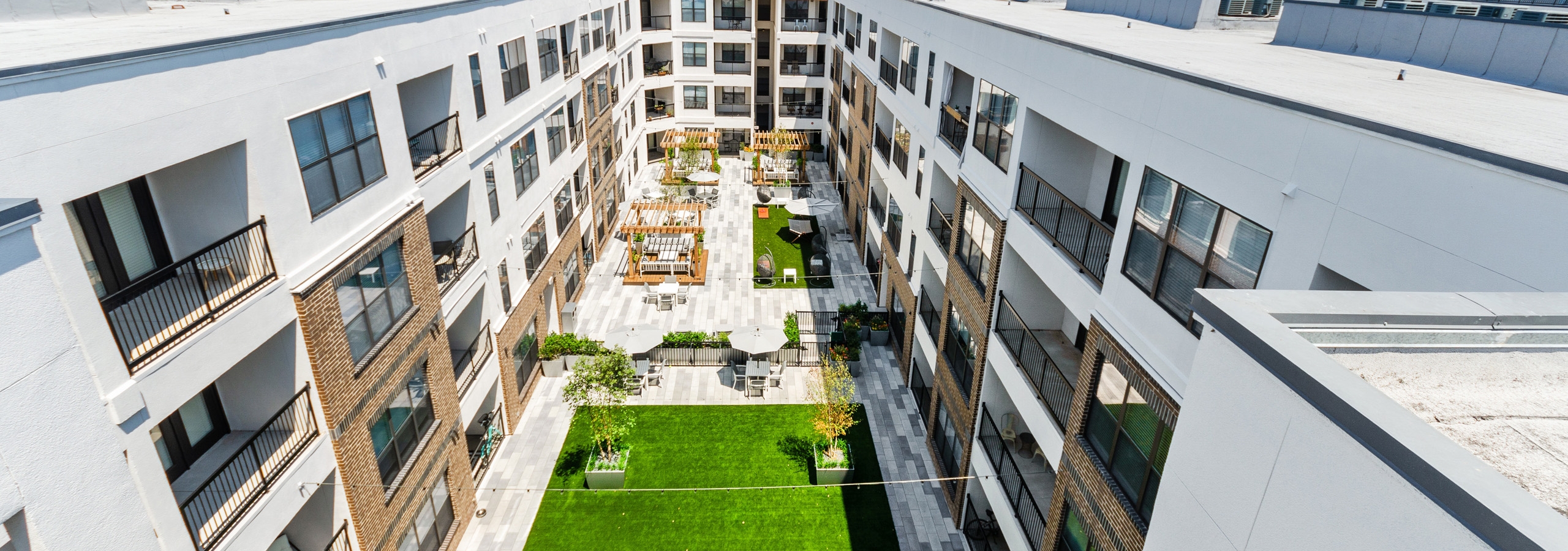 Aerial view of AMLI Quadrangle landscaped courtyard with wood pergolas and ample seating and large grassy area with trees