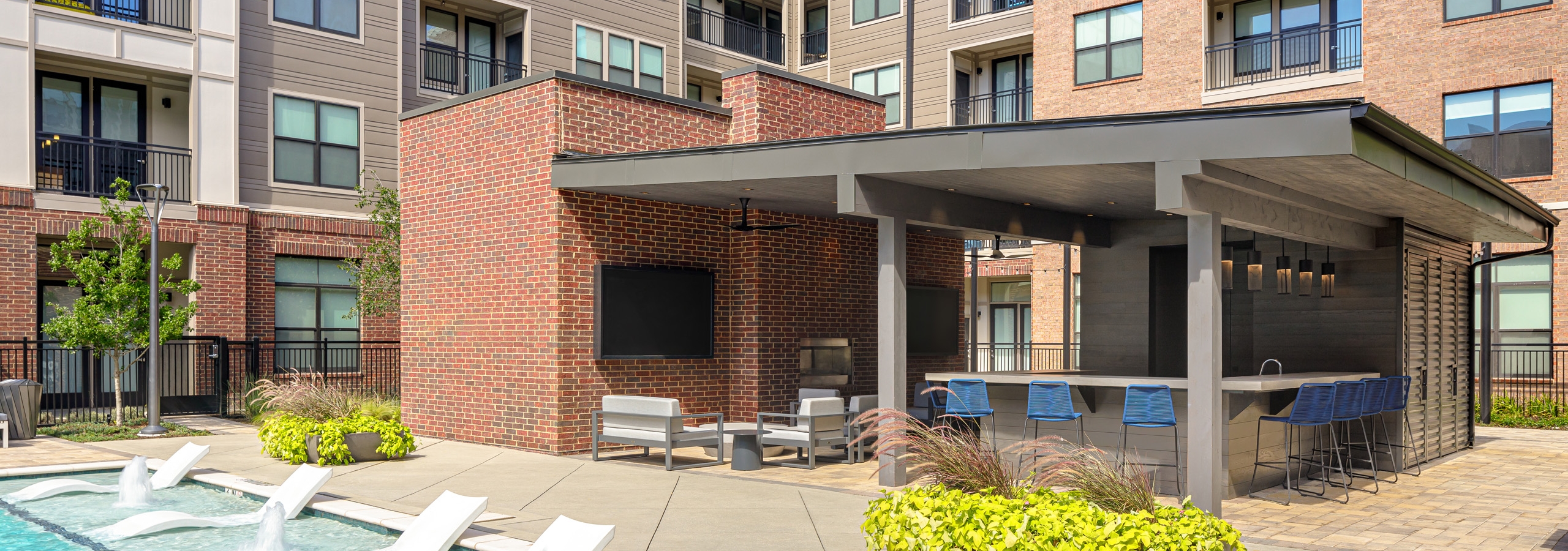 AMLI Addison poolside entertainment cabana with two large screen televisions and an outdoor kitchen with barstool seating