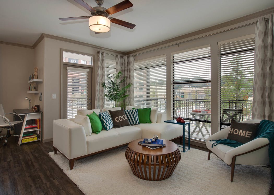 Apartment living room at AMLI Ponce Park with cream walls and dark hardwood with large windows letting in natural sunlight