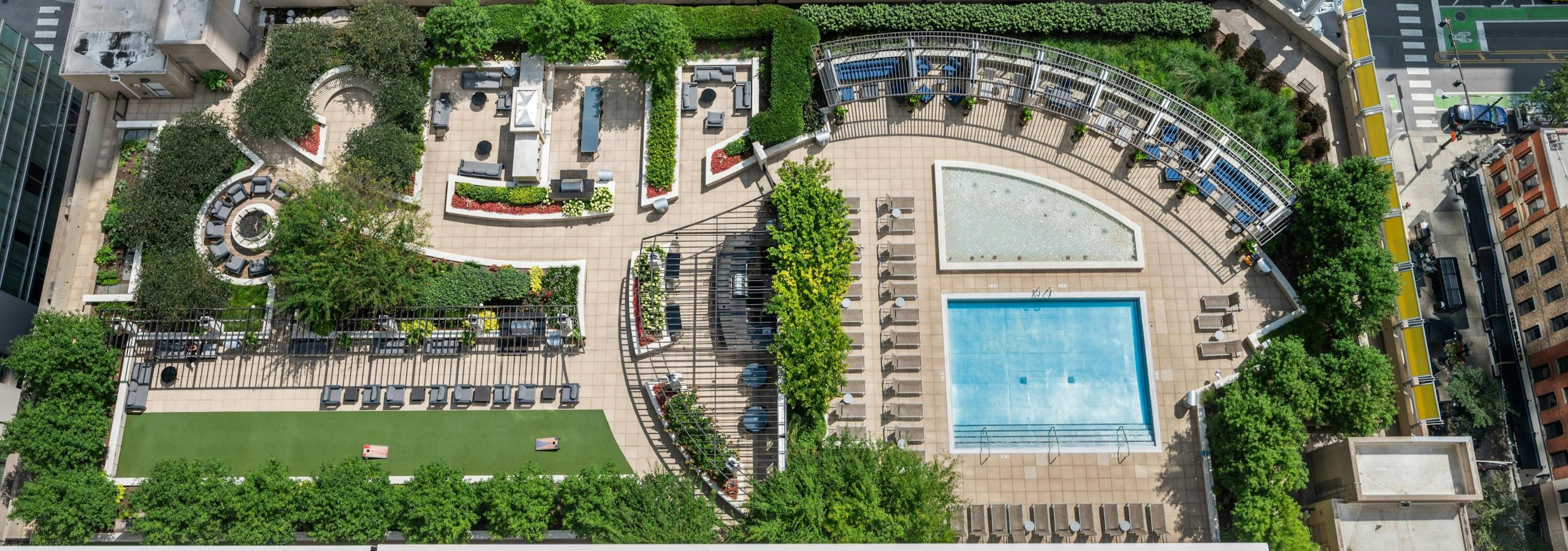 Aerial view of landscaped rooftop amenity deck with pool and cabanas and seating areas at AMLI River North with street below