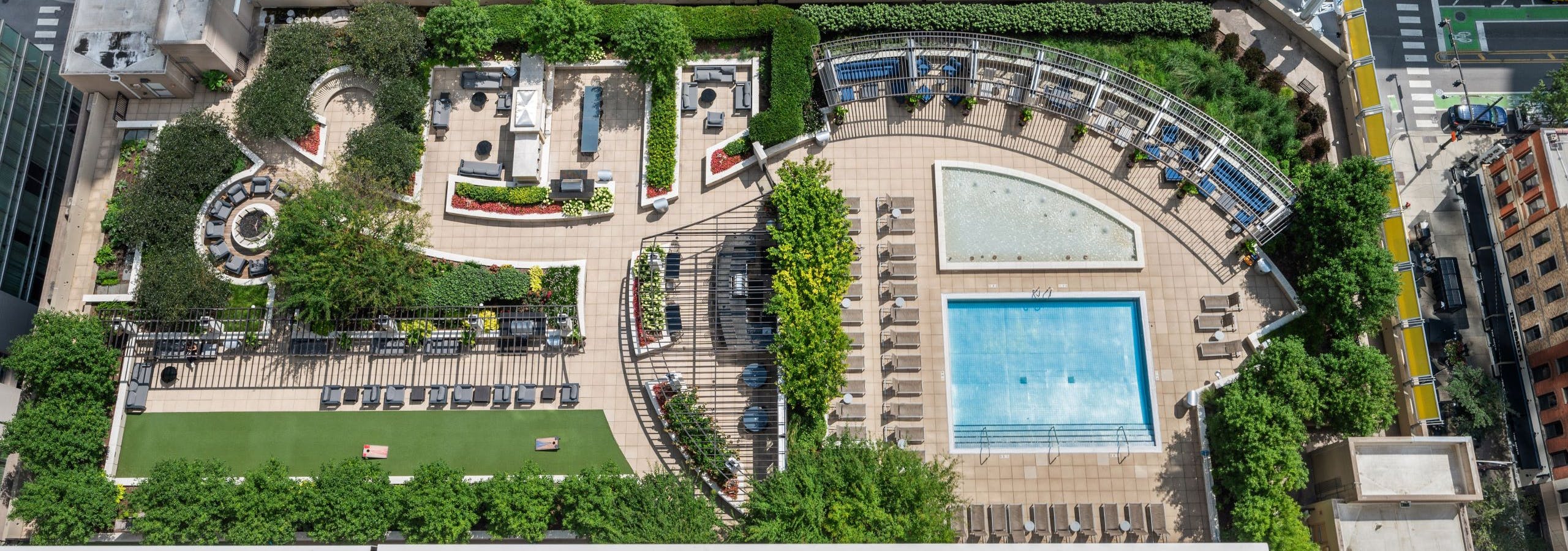 Aerial view of landscaped rooftop amenity deck with pool and cabanas and seating areas at AMLI River North with street below