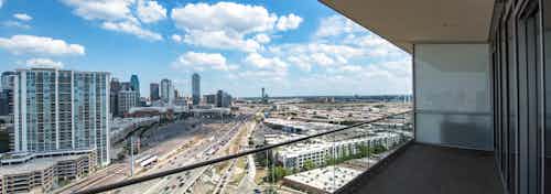 Daytime exterior view of AMLI Design District penthouse apartment balcony with glass railing overlooking the city