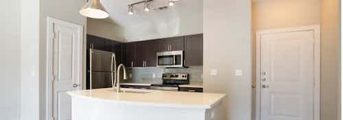 Redesigned kitchen at AMLI Inverness apartments with an island with white granite counter top with view of the front door