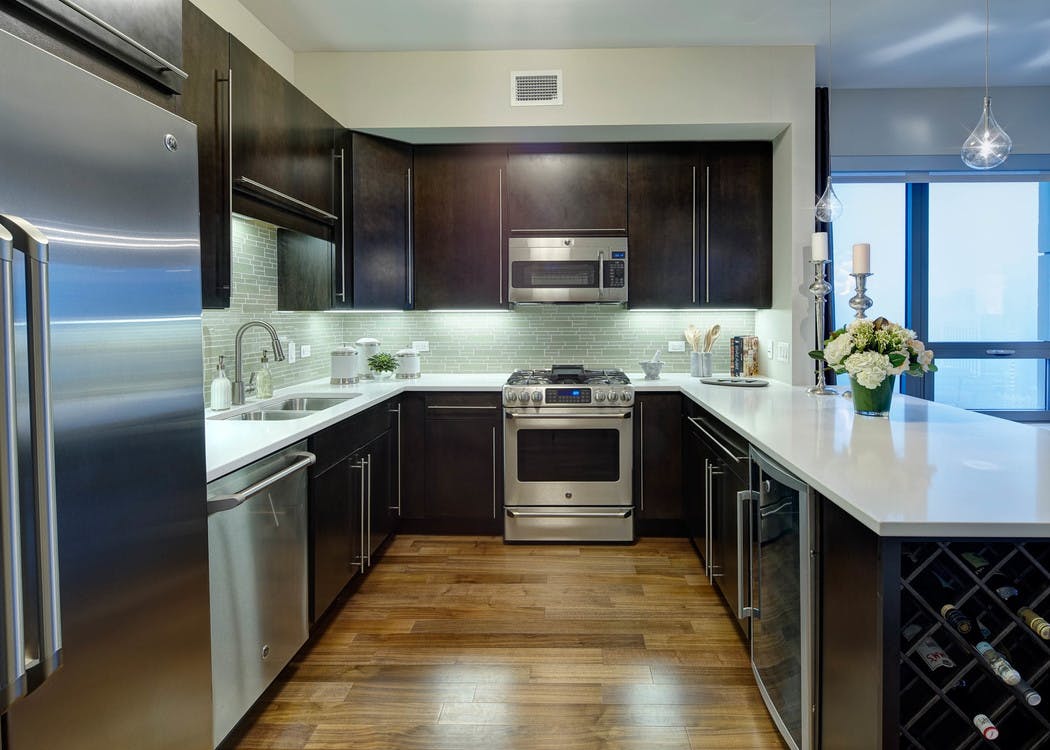 Interior view of an AMLI River North penthouse kitchen next to a floor to ceiling window overlooking the city buildings
