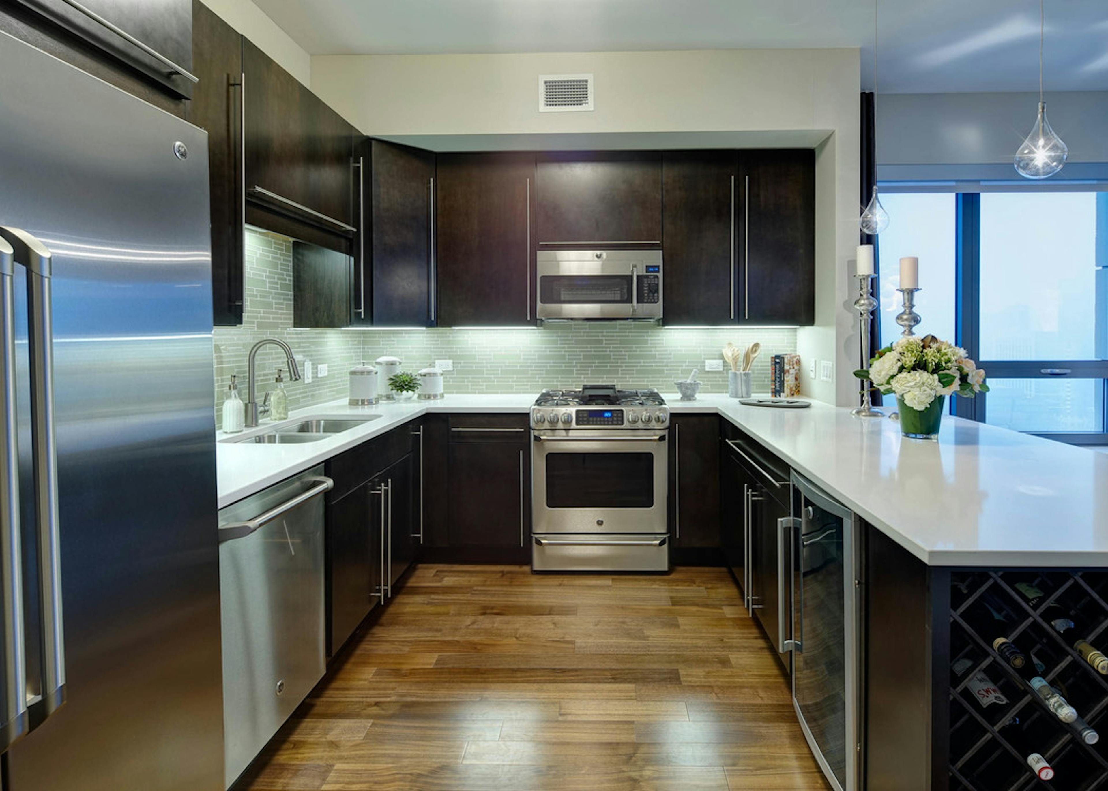 Interior view of an AMLI River North penthouse kitchen next to a floor to ceiling window overlooking the city buildings