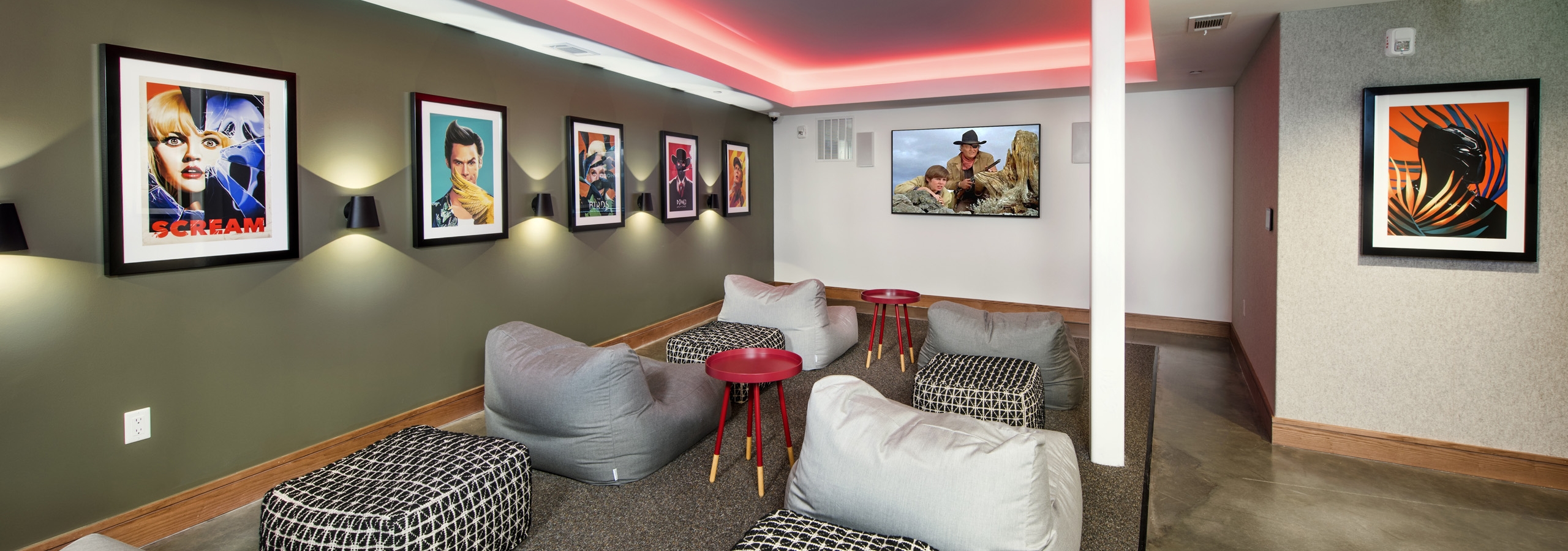 AMLI Lenox theater room with bright pink ceiling lights and big screen TV and multiple bean bag chairs with colorful artwork
