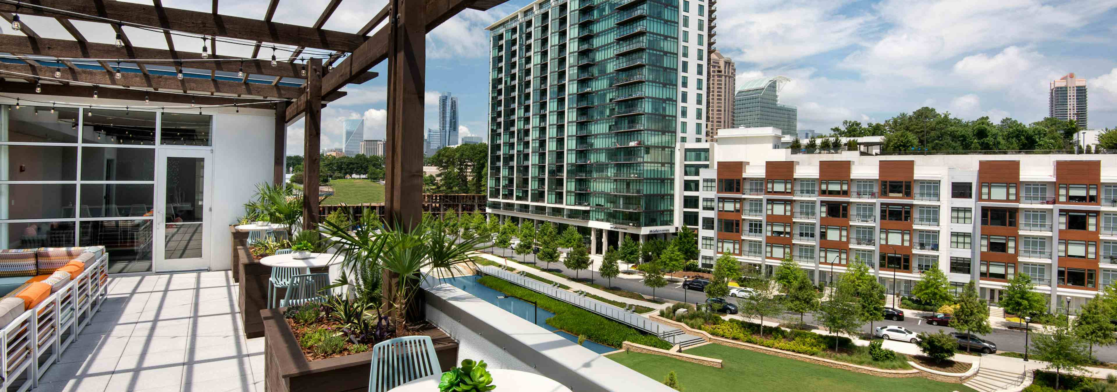 AMLI Buckhead skydeck with a pergola for seating area and a view of vibrant grass and modern buildings under a cloudy sky