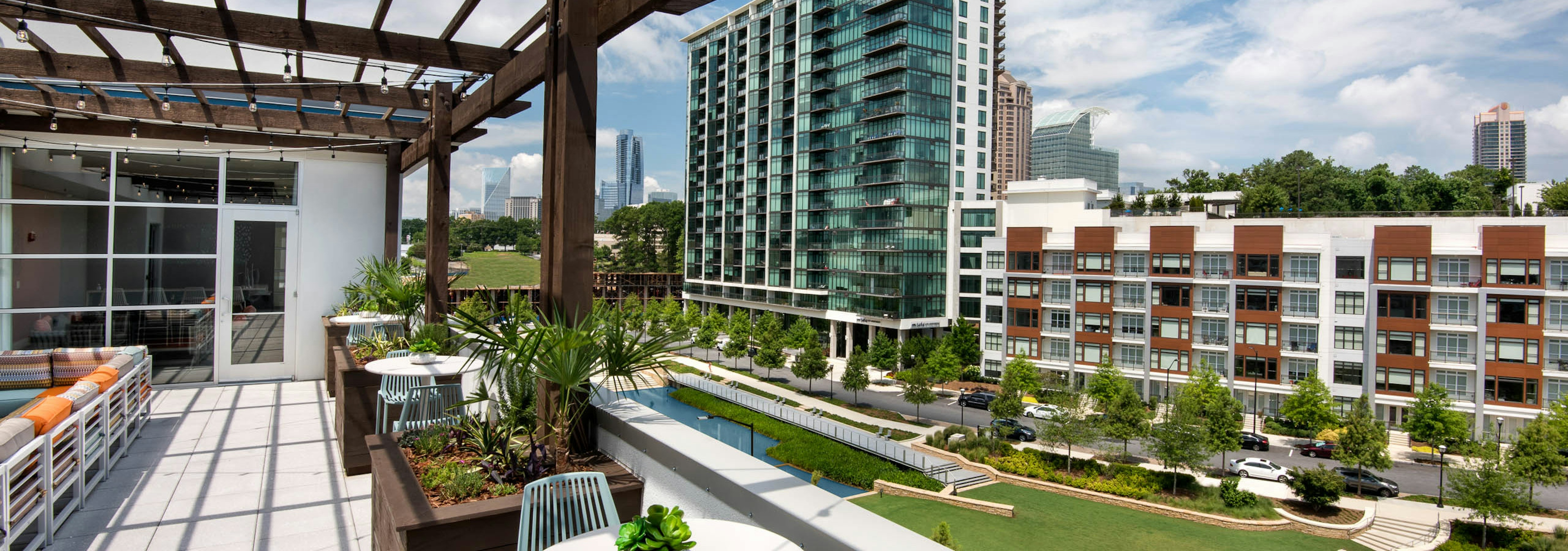 AMLI Buckhead skydeck with a pergola for seating area and a view of vibrant grass and modern buildings under a cloudy sky