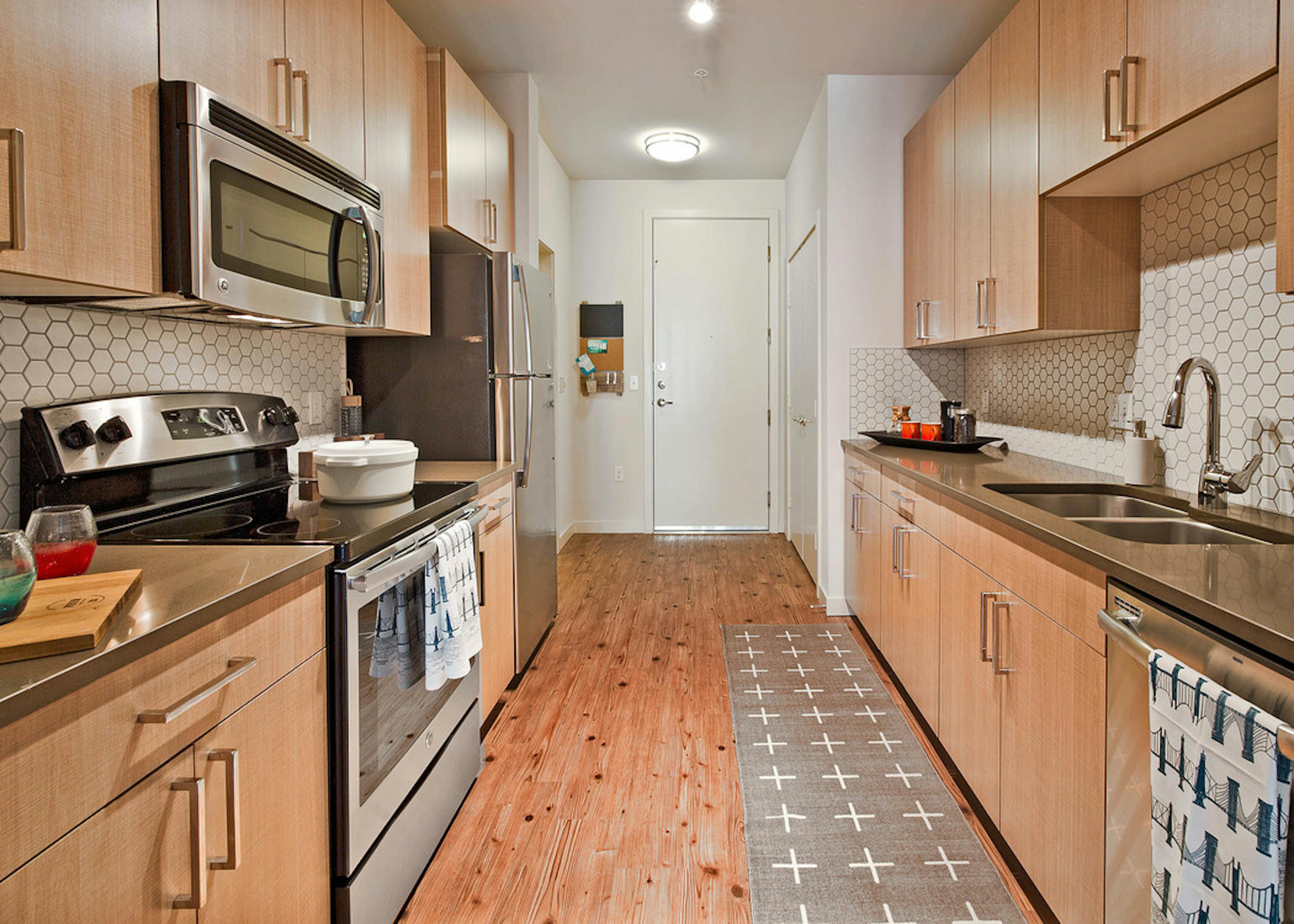 Apartment kitchen at AMLI South Lake Union with light cabinets and grey quartz counters and white honeycomb back splash