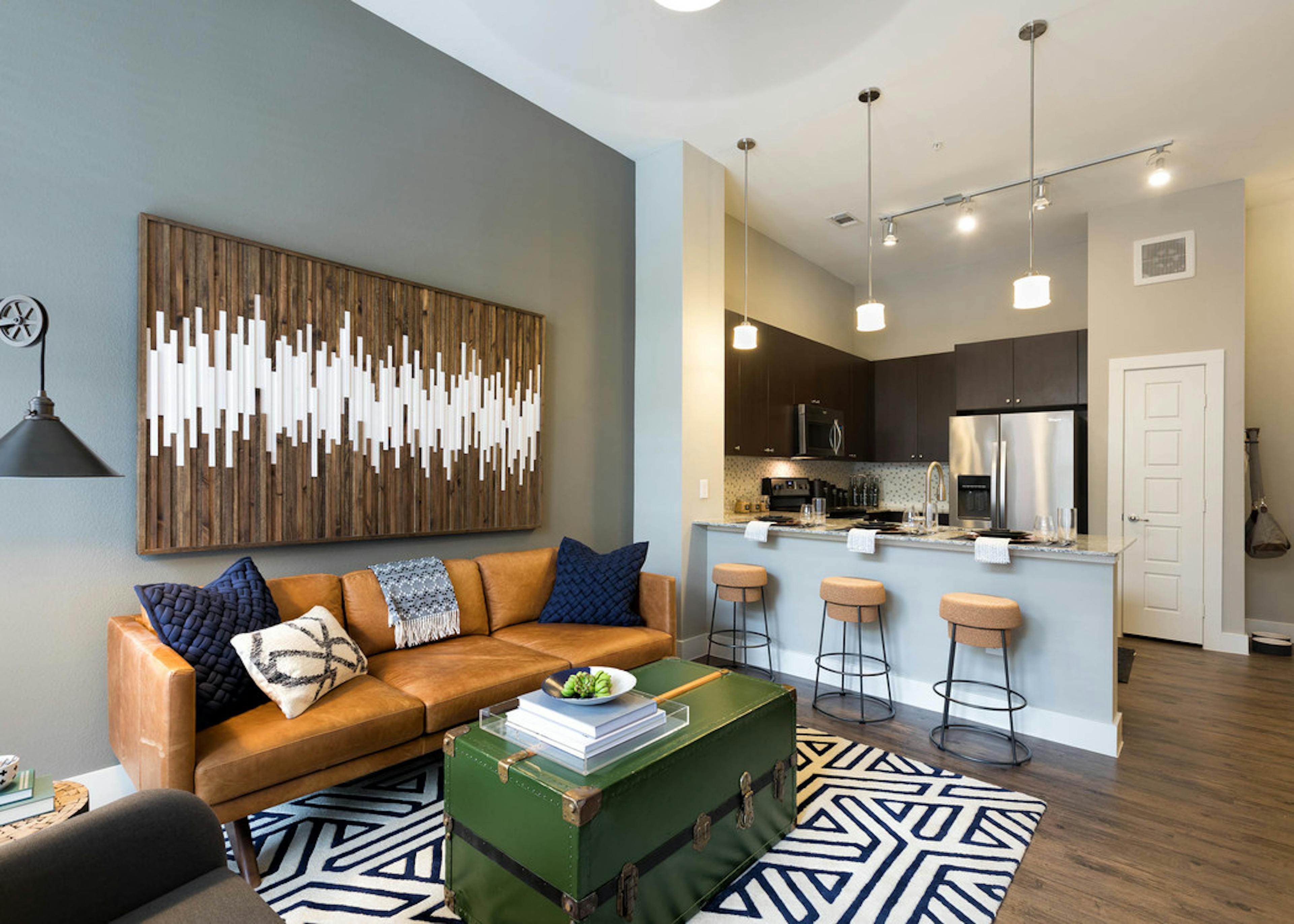Interior view of AMLI Frisco Crossing apartment kitchen with stainless steel appliances and living room with couch and table
