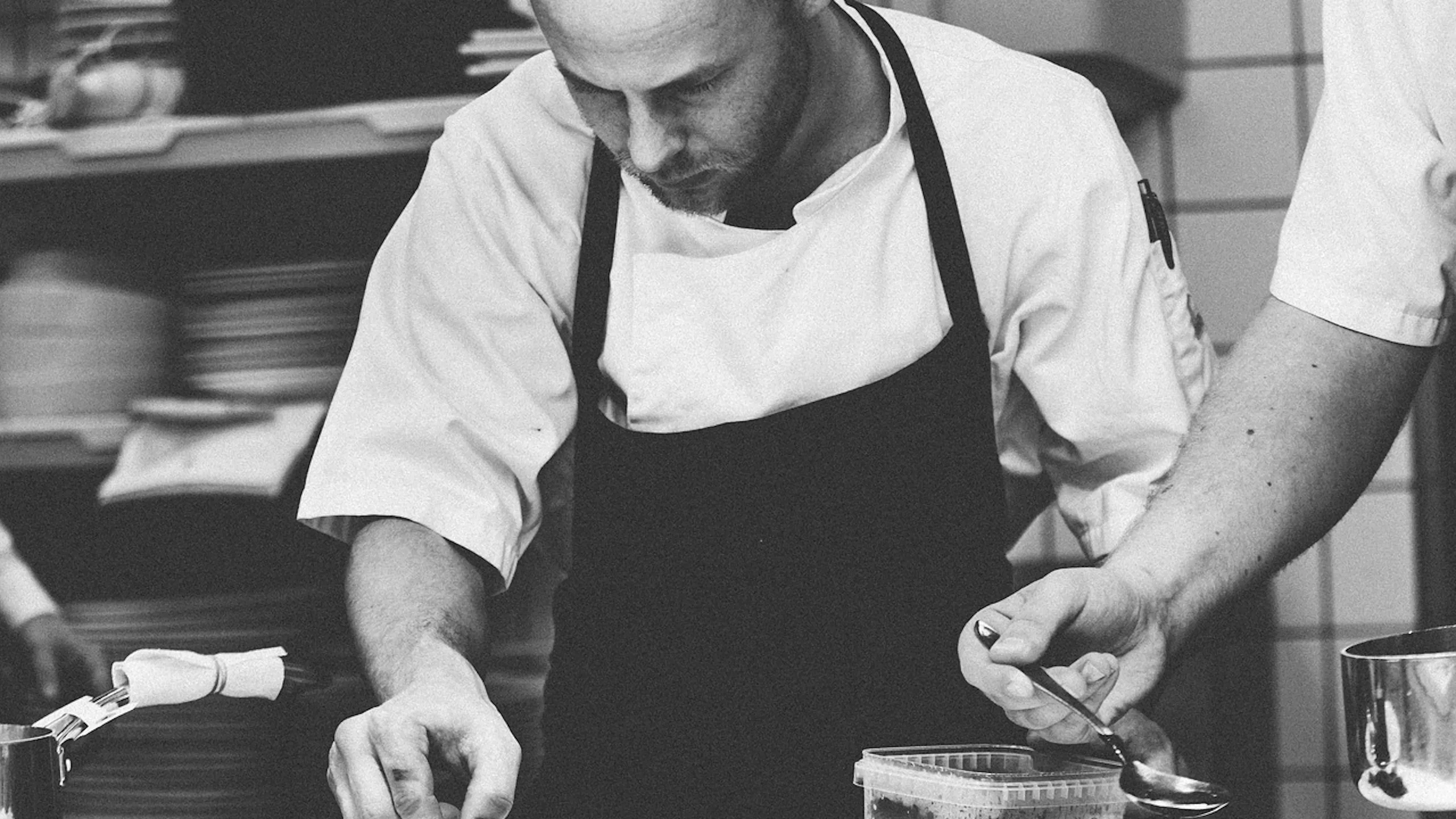 A chef in a kitchen carefully arranging a dessert on a small plate