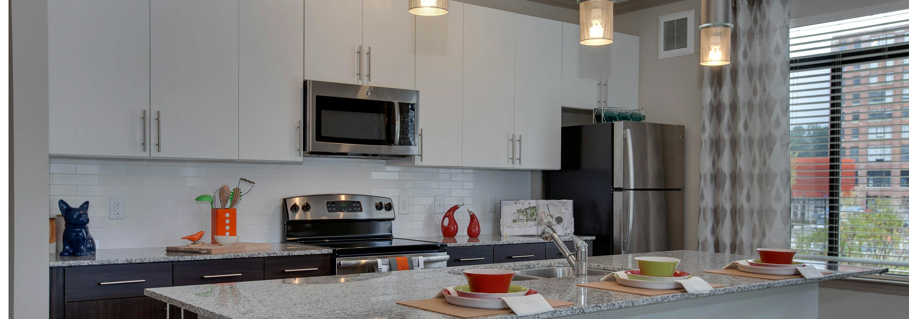 AMLI Ponce Park kitchen with stainless steel microwave nested in white cabinets above an oven nested in dark lower cabinets