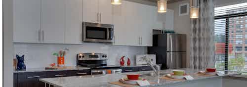 AMLI Ponce Park kitchen with stainless steel microwave nested in white cabinets above an oven nested in dark lower cabinets