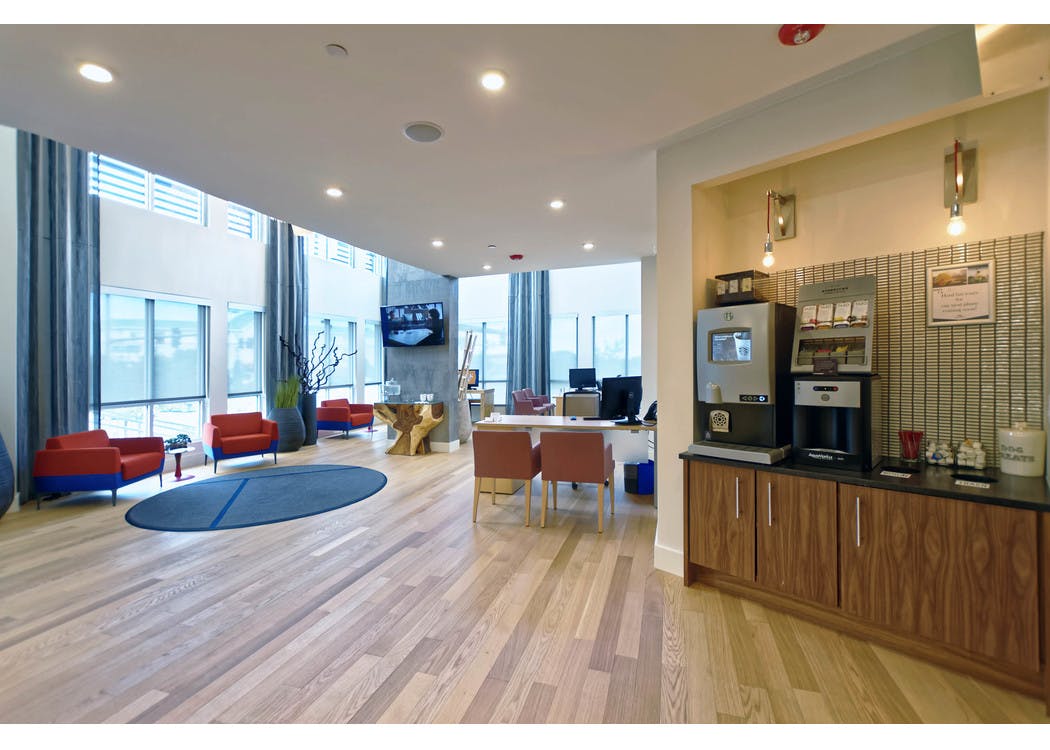 Leasing office at AMLI Dry Creek apartments with a coffee machine and desks and chairs with computers and view of front door
