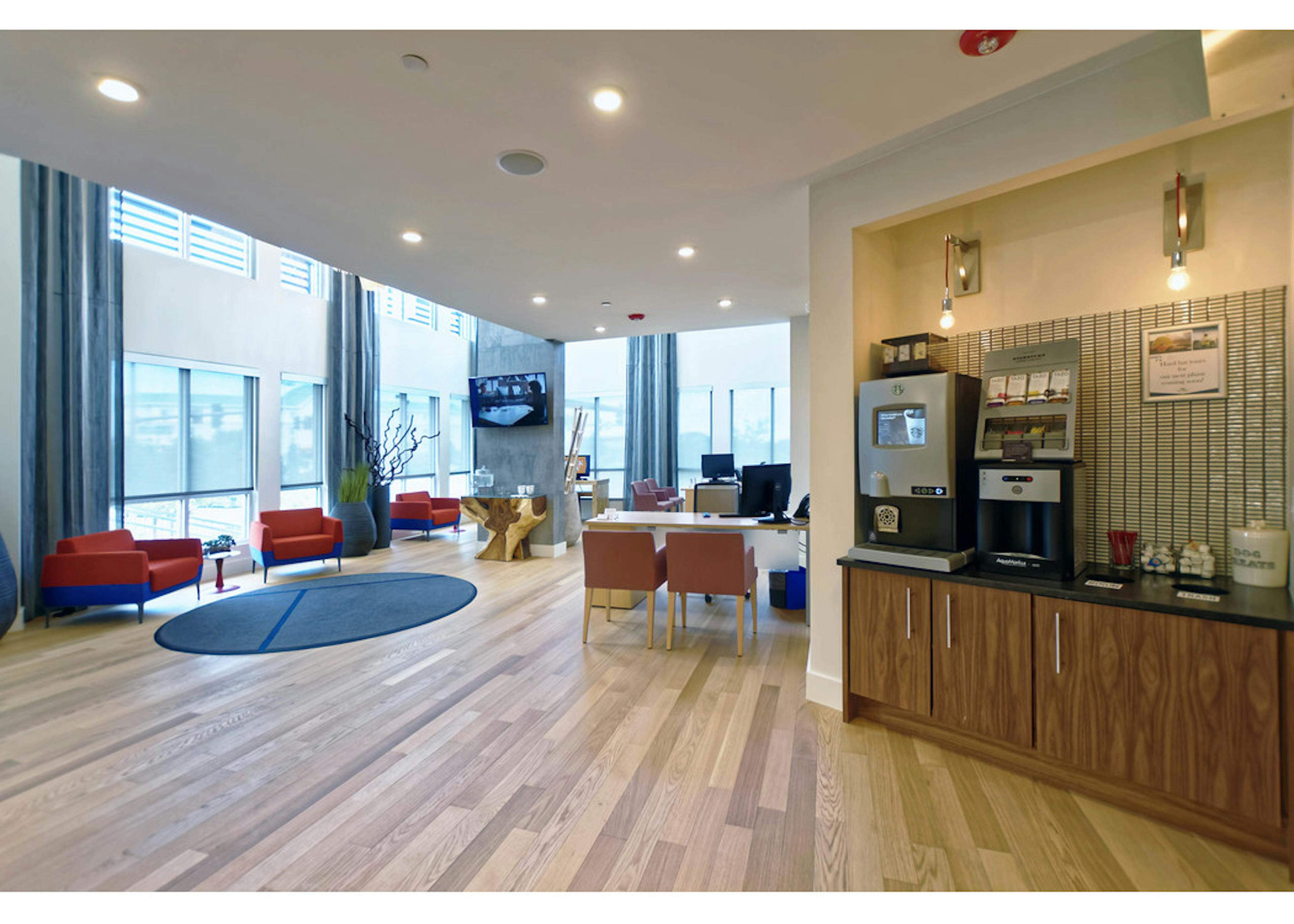 Leasing office at AMLI Dry Creek apartments with a coffee machine and desks and chairs with computers and view of front door