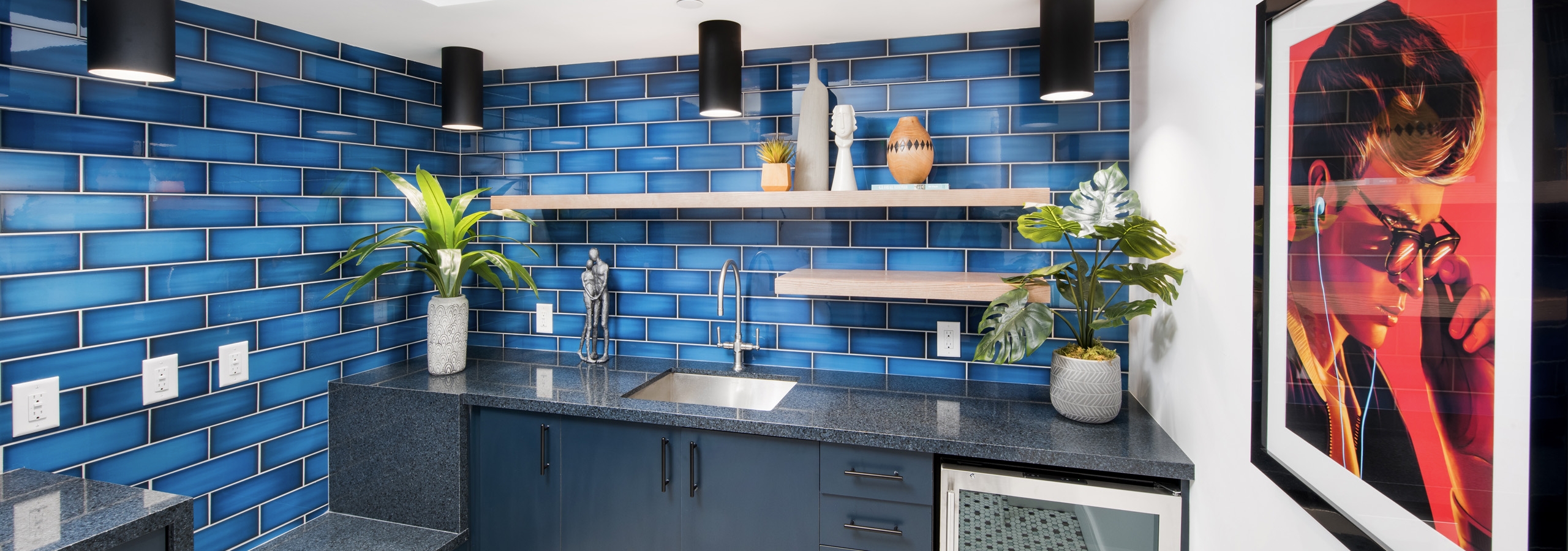 AMLI Lenox amenity kitchen area with blue tiled walls and sink and refrigerator and bright painting on the wall