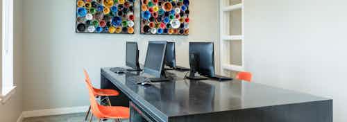 Interior view of business center at AMLI Frisco Crossing apartment building with four computer stations and chairs