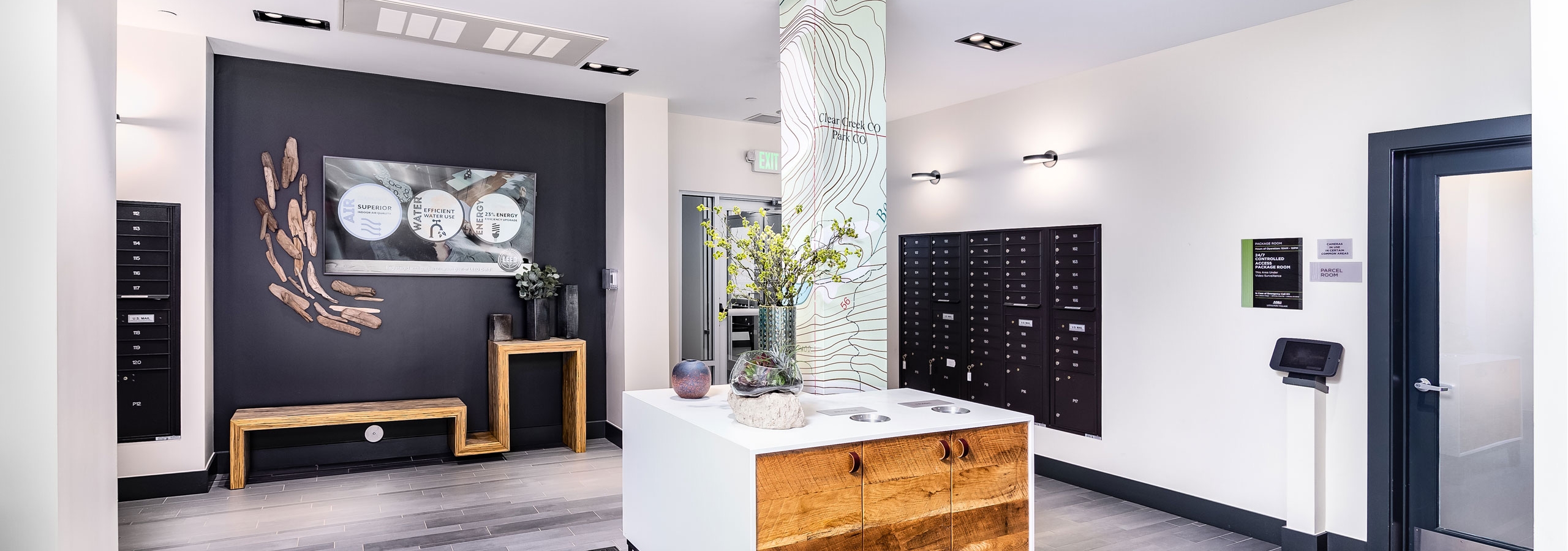 Interior of AML Littleton Village mail room lobby with stylish custome furniture and mission statement on black accent wall