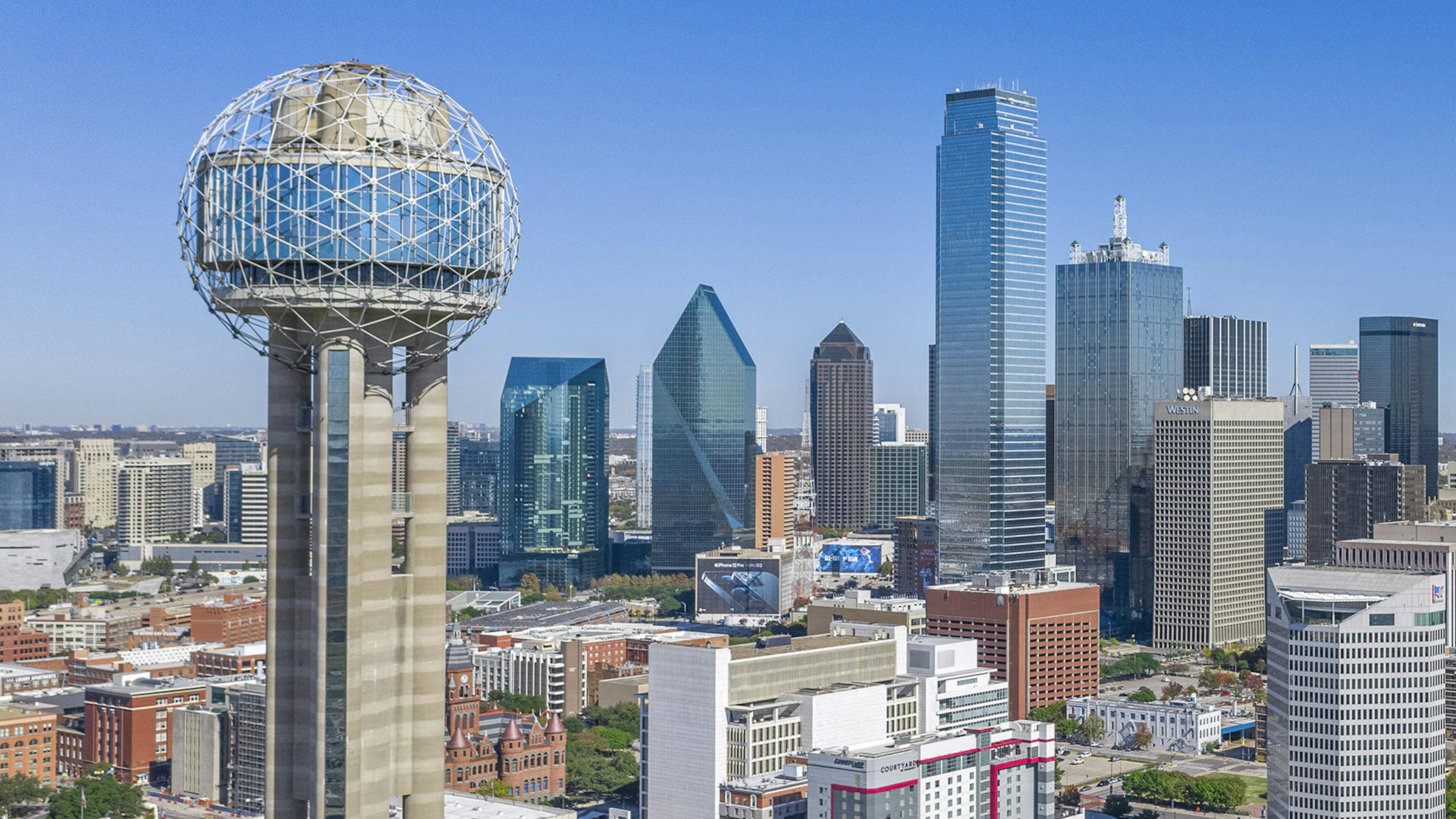 Aerial day view of downtown Dallas with the Reunion Tower in front and skyscrapers and AMLI Fountain Place in the background