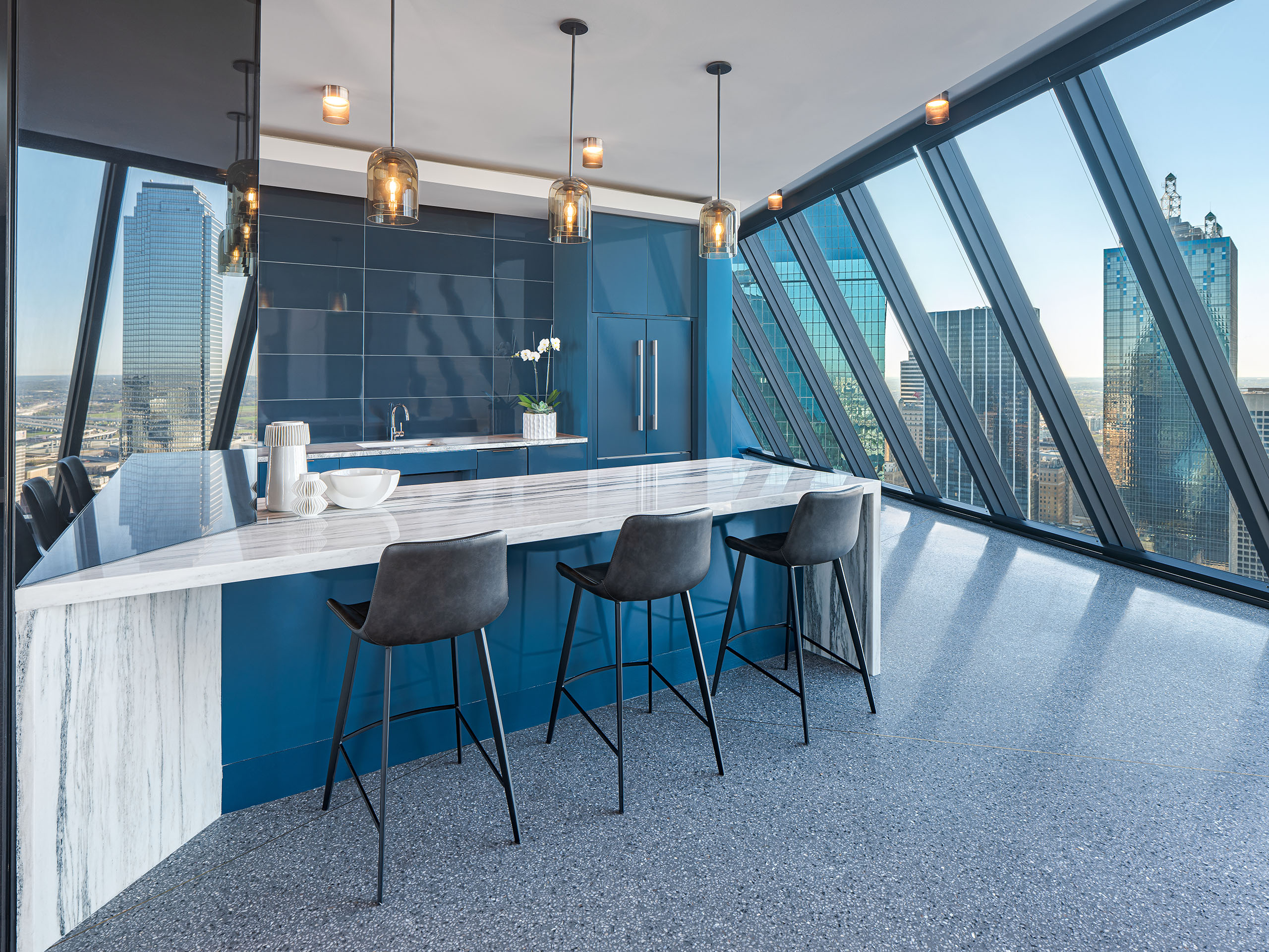 Sky lounge at AMLI Fountain Place apartments with white and grey counter and blue cabinets and dozens of hanging lights 