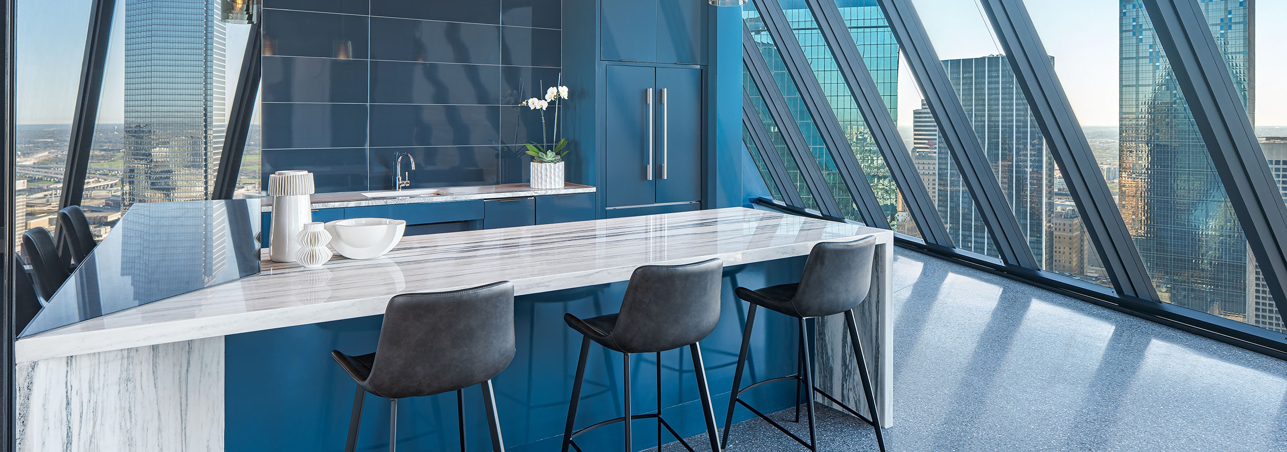 Sky lounge at AMLI Fountain Place apartments with white and grey counter and blue cabinets and dozens of hanging lights