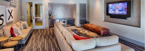 Interior view of the media room at AMLI Denargo Market apartments with large couches a small fridge and large television