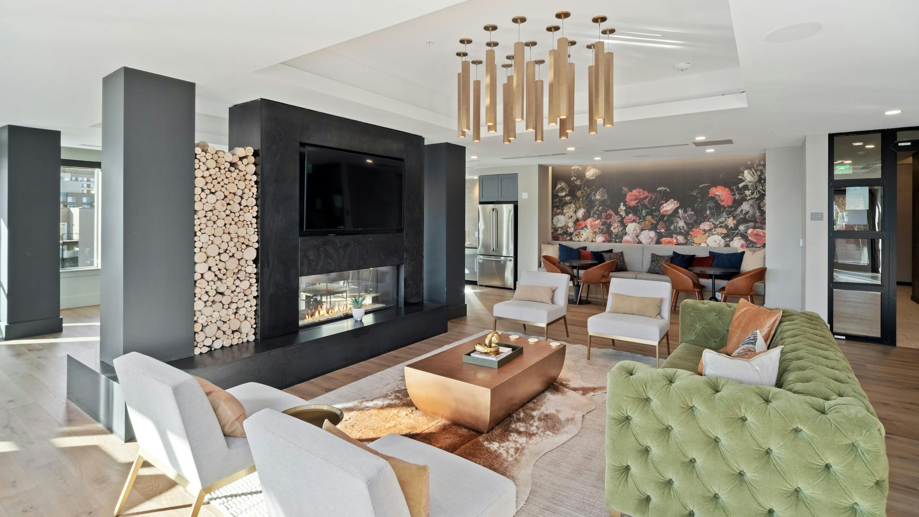 AMLI at Uptown resident lounge with vintage style furniture placed around a modern fireplace with mounted flat screen TV 