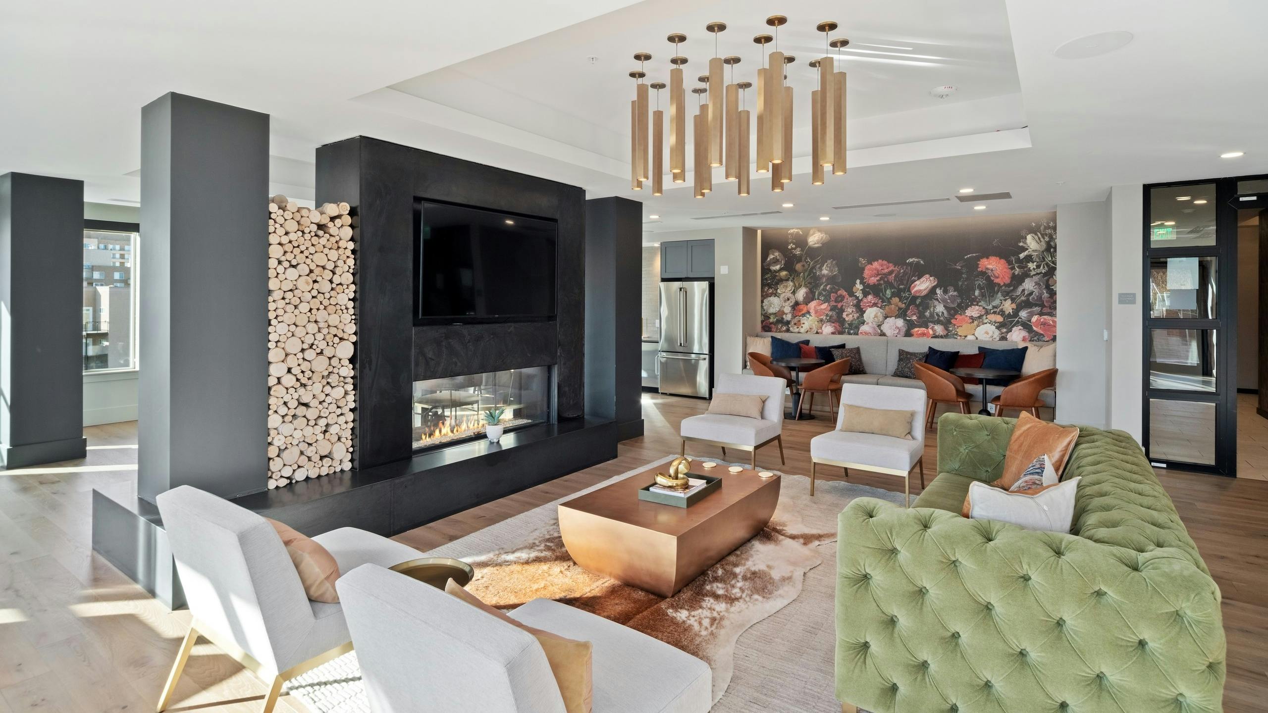 AMLI at Uptown resident lounge with vintage style furniture placed around a modern fireplace with mounted flat screen TV