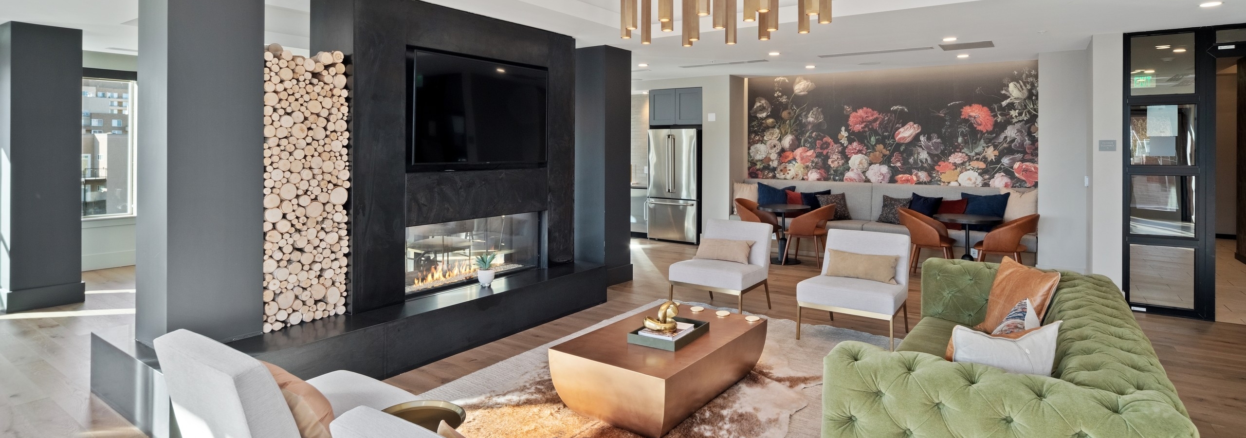 AMLI at Uptown resident lounge with vintage style furniture placed around a modern fireplace with mounted flat screen TV