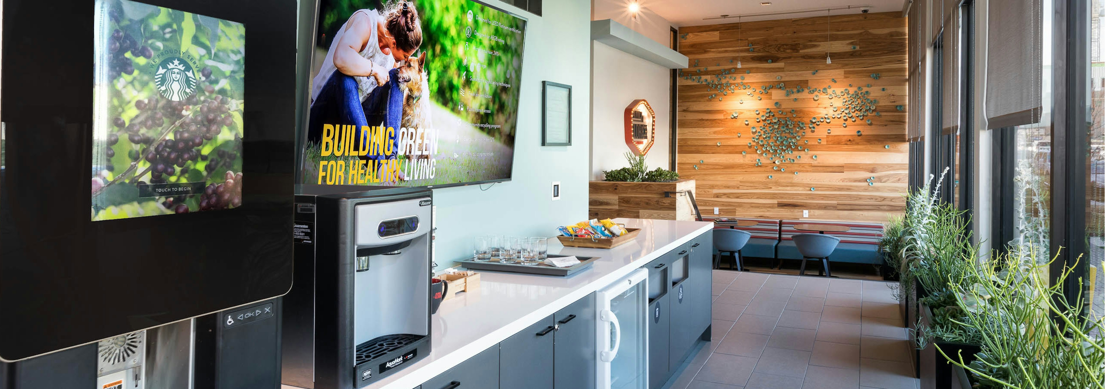 Java cafe at AMLI on Aldrich with coffee machine resting on a white countertop with grey cabinets and textured wood wall