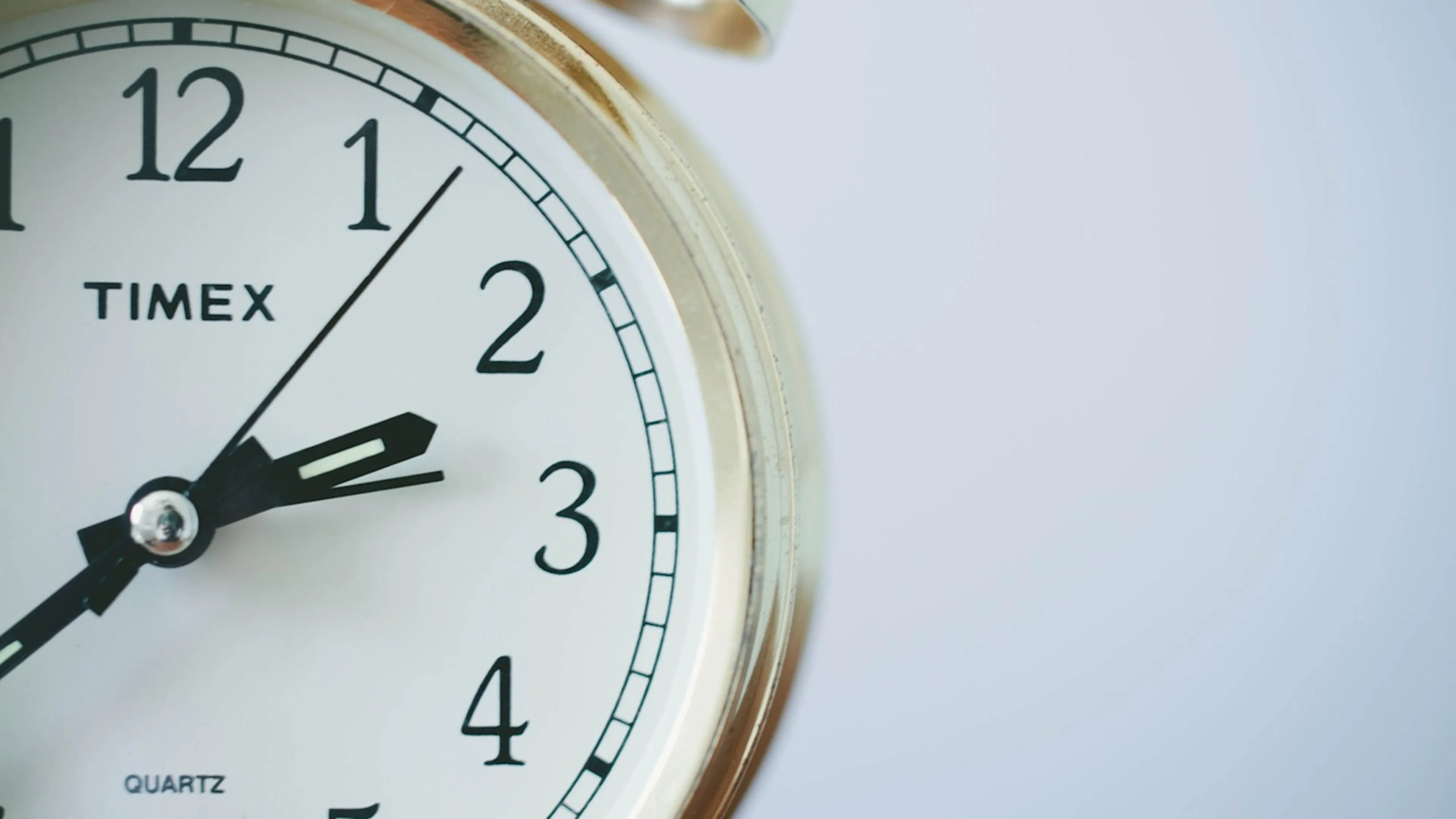 right half of a golden alarm clock with the clock hands showing it's about 2:40 