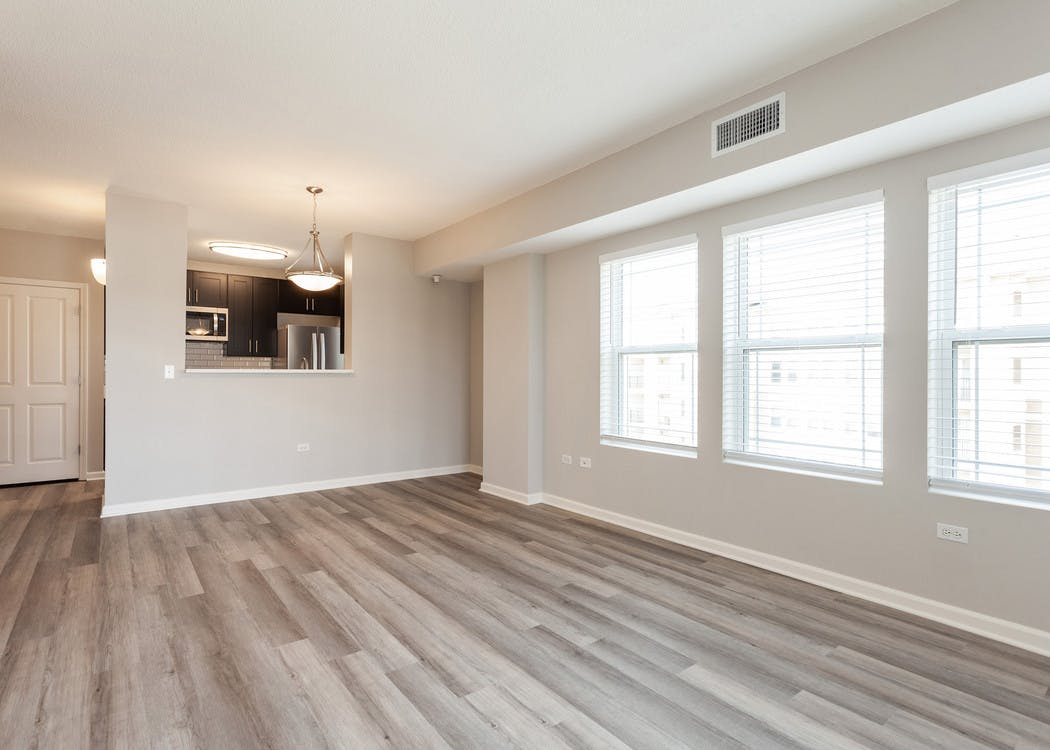 Interior daytime view of spacious living area at AMLI at Seven Bridges with hardwood-style plank floors and large windows