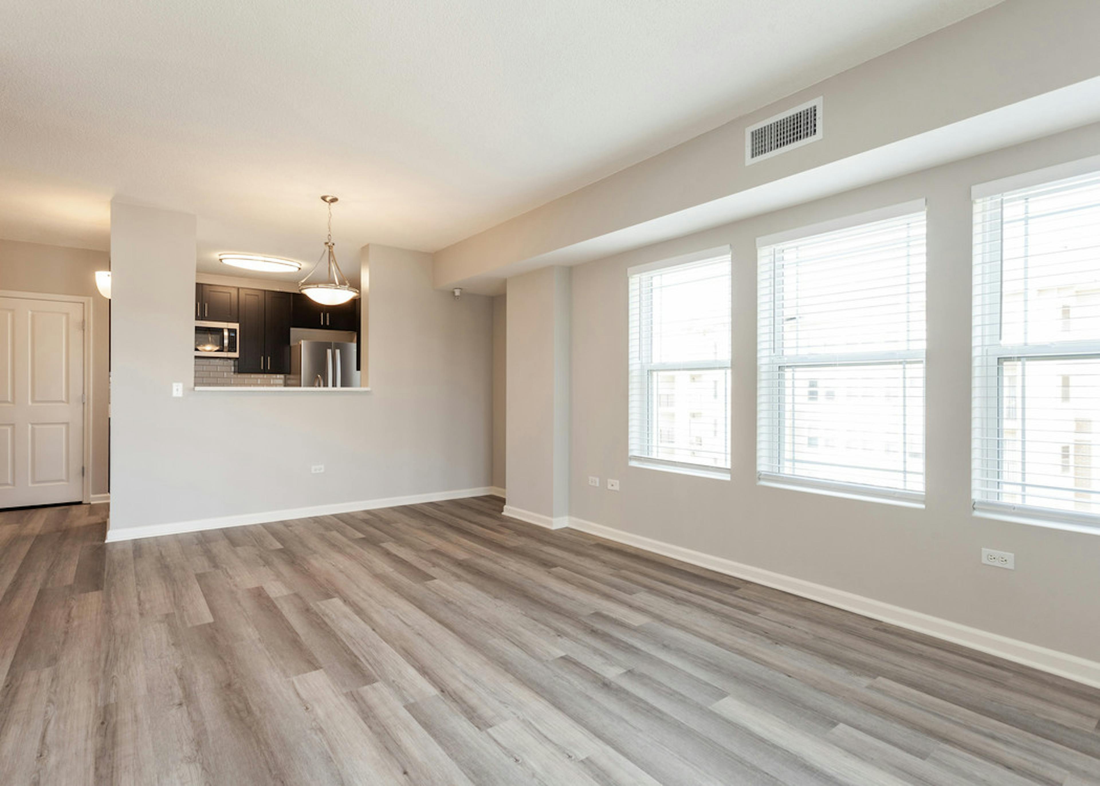 Interior daytime view of spacious living area at AMLI at Seven Bridges with hardwood-style plank floors and large windows