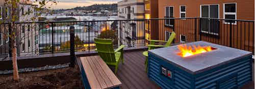 Rooftop deck view from AMLI Mark24 with a flaming firepit and Salmon Bay in the distance under a cloudy evening Seattle sky