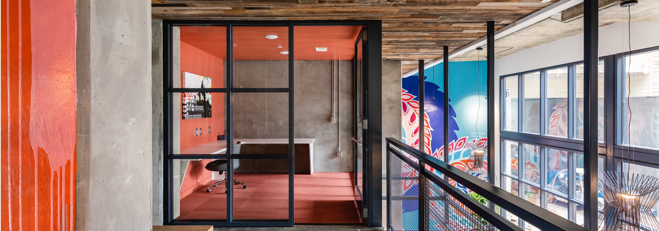 AMLI Westside community work spaces with concrete flooring and colorful private offices with glass doors and large windows