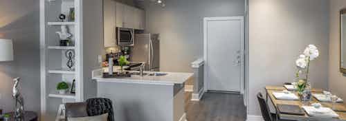 Kitchen and dining room at AMLI Eastside apartments with vinyl wood floors and white cabinets and stainless appliances