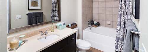 Interior view of AMLI RidgeGate bathroom with travertine countertops and oversized soaking tub with ceramic tile surround