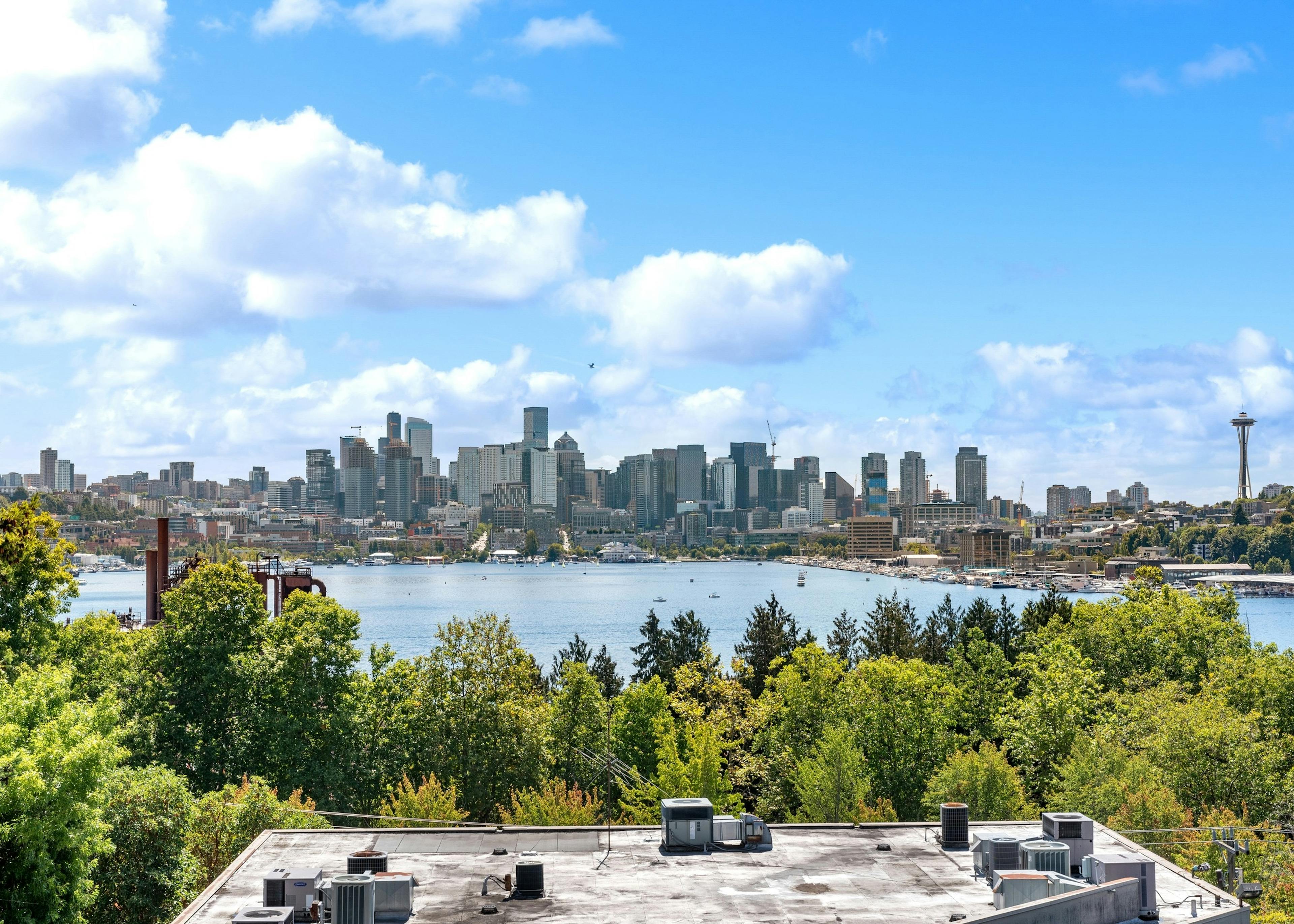 Exterior view from AMLI Wallingford with view of building rooftops and green trees and Lake union and the Seattle skyline