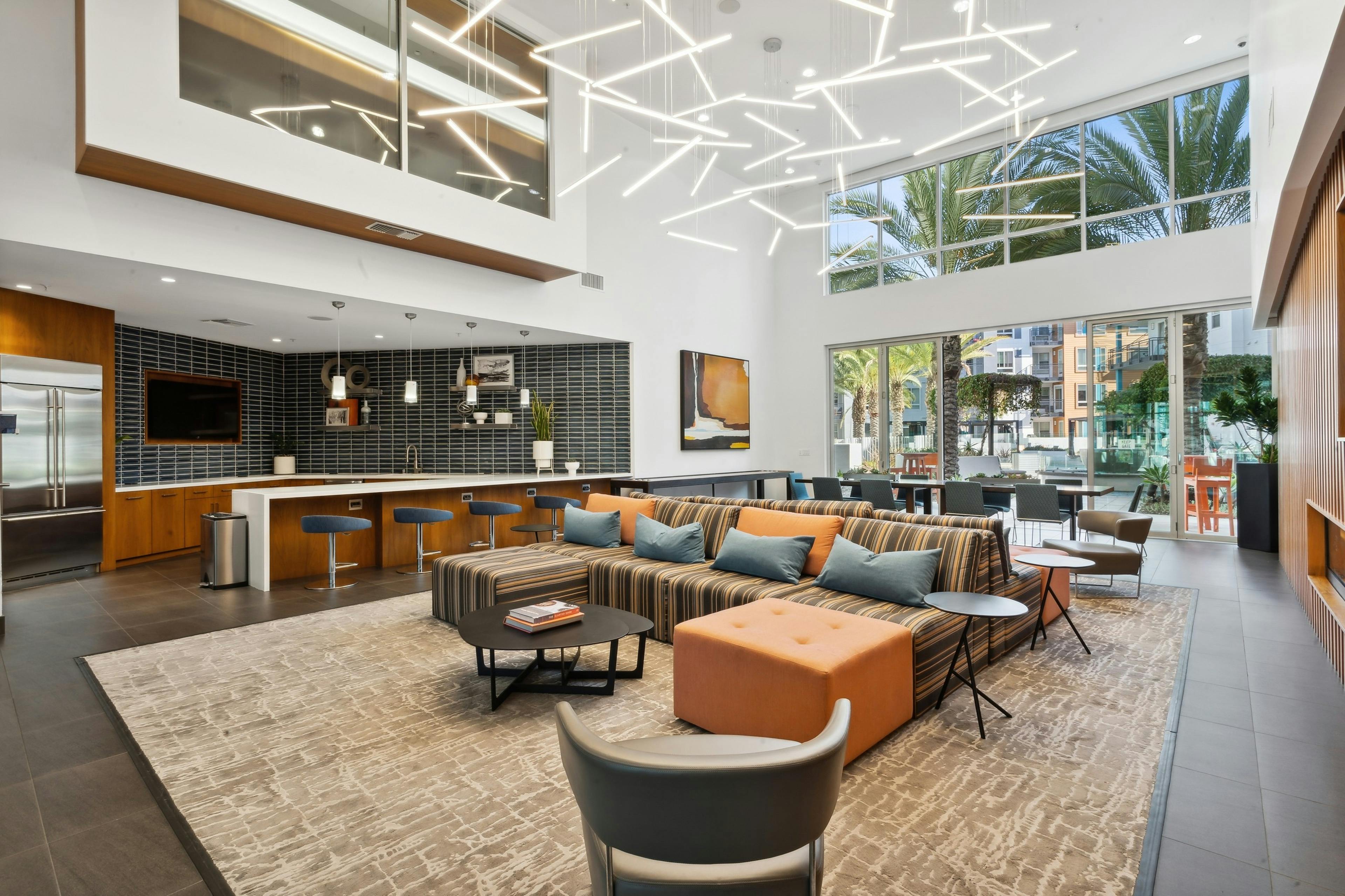 Furnished resident clubroom with serving kitchen and glass doors facing the pool area at AMLI Uptown Orange apartments 