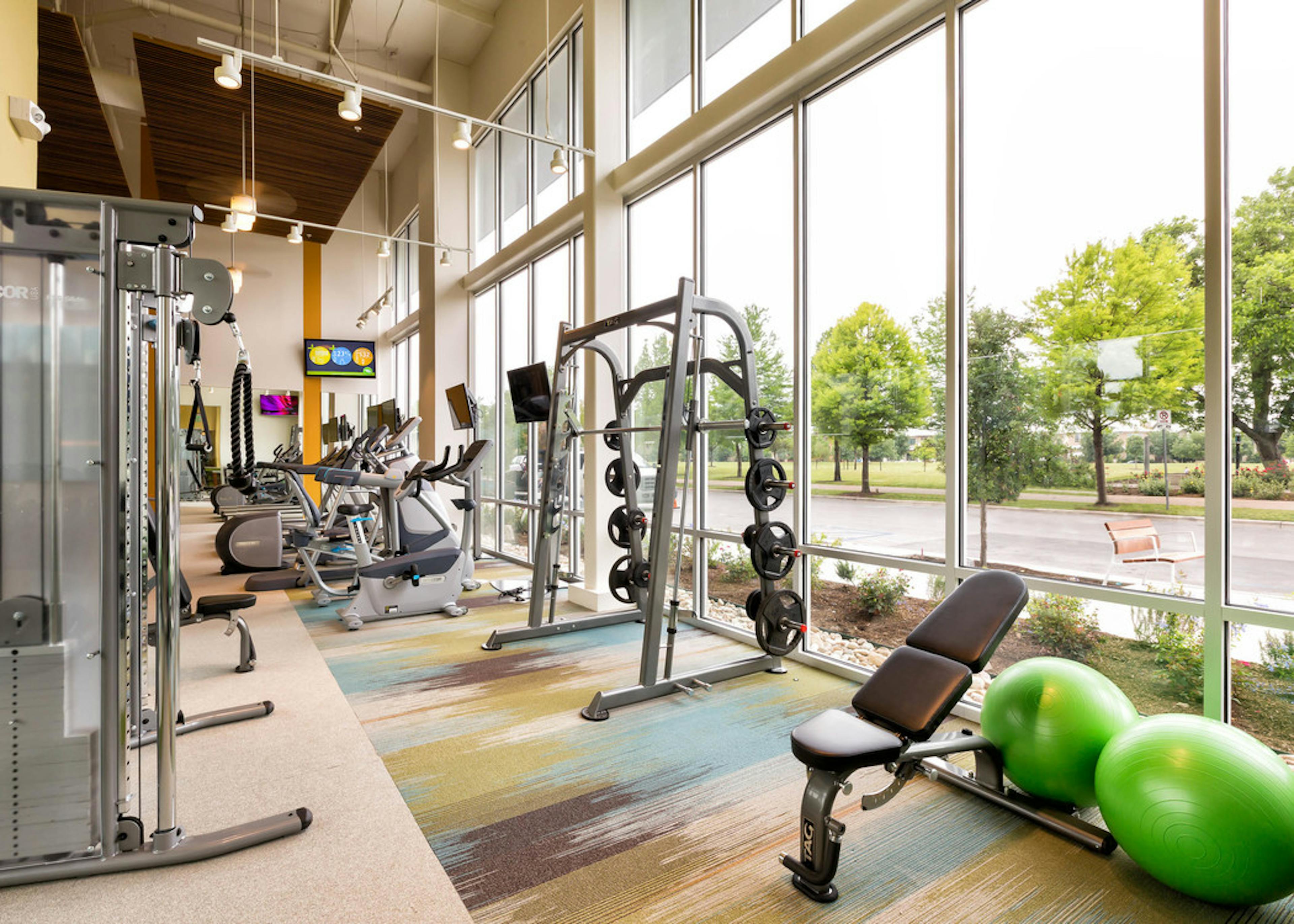Interior view of fitness center at AMLI at Mueller featuring a variety of weight machines and floor to ceiling windows