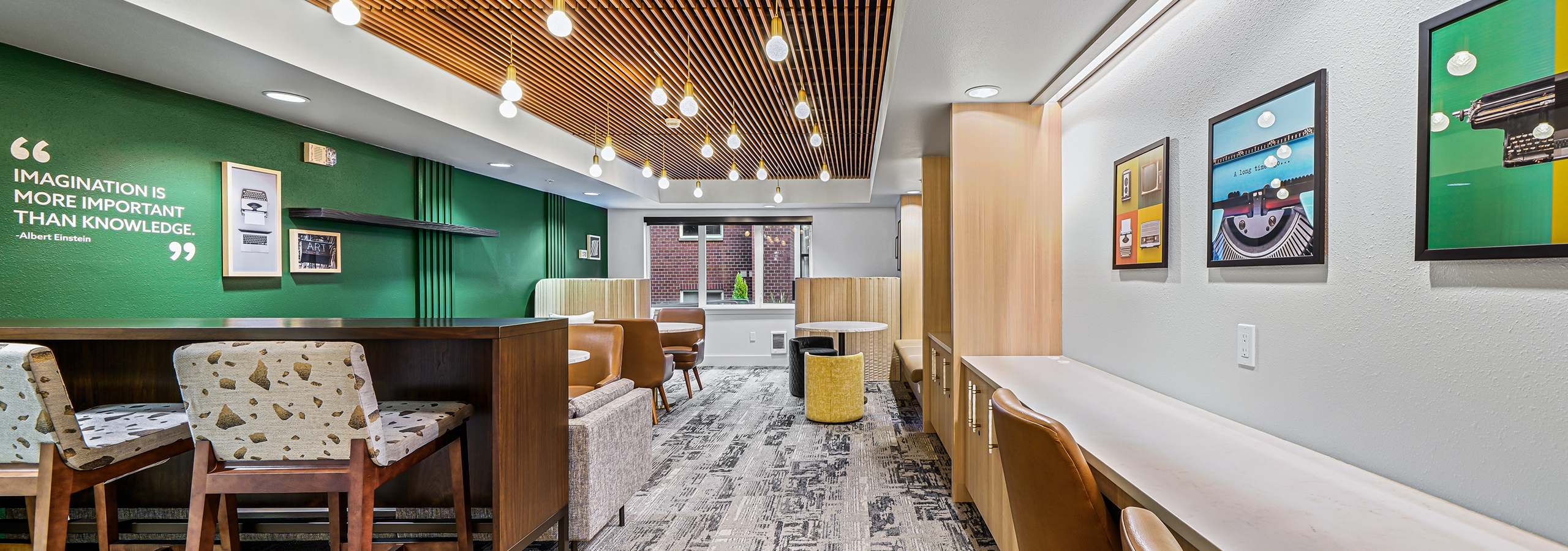 Green wall with wood paneled ceiling and long counter with chairs in resident lounge at AMLI Bellevue Park apartments